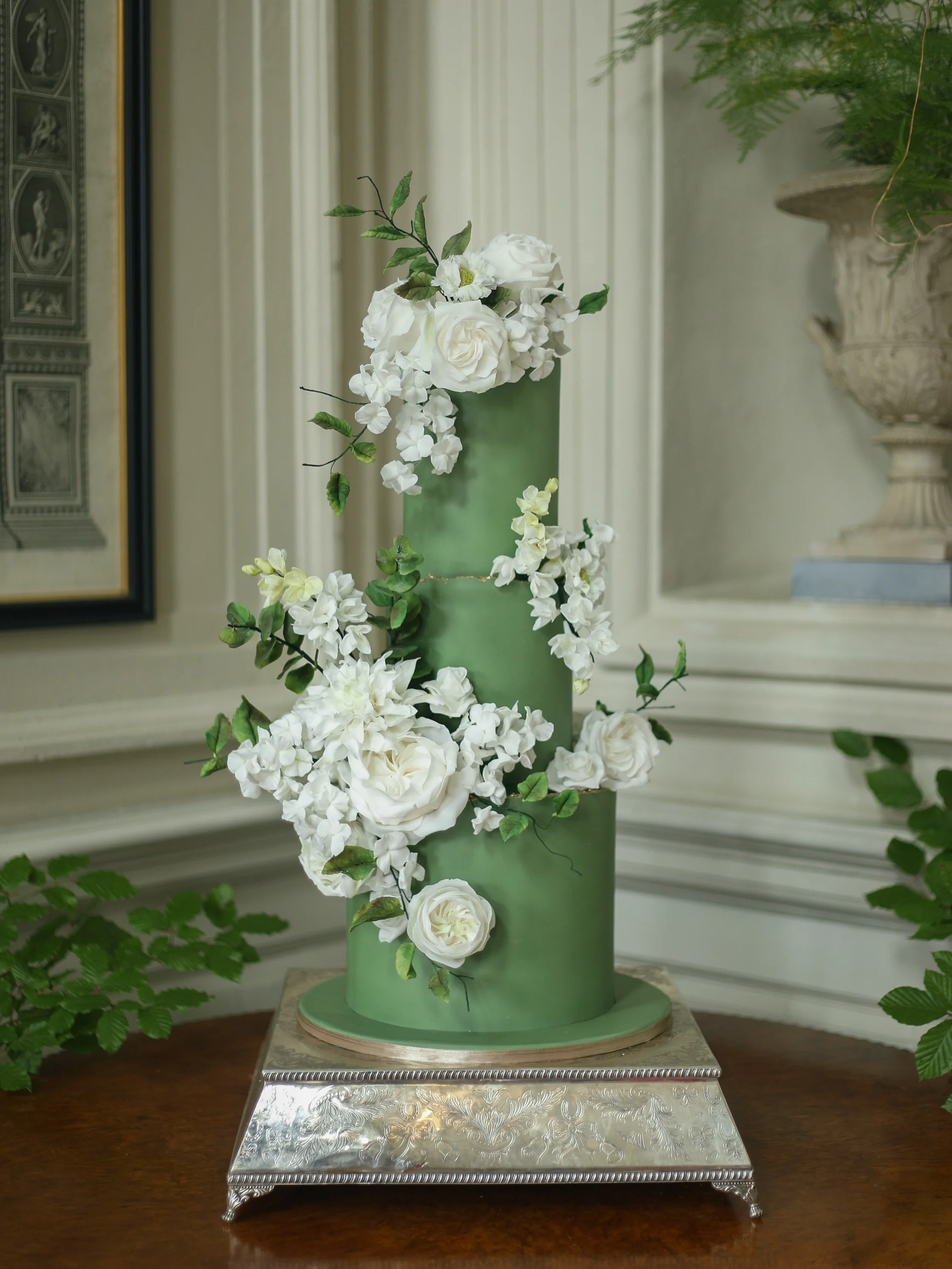 Undoubtedly one of our favourite wedding cakes of the year!

A beautifully muted olive green provides the most sophisticated canvas for delicate, sculptural sugar flower bouquets, cascading gracefully across this three-tiered beauty. Understated yet 
