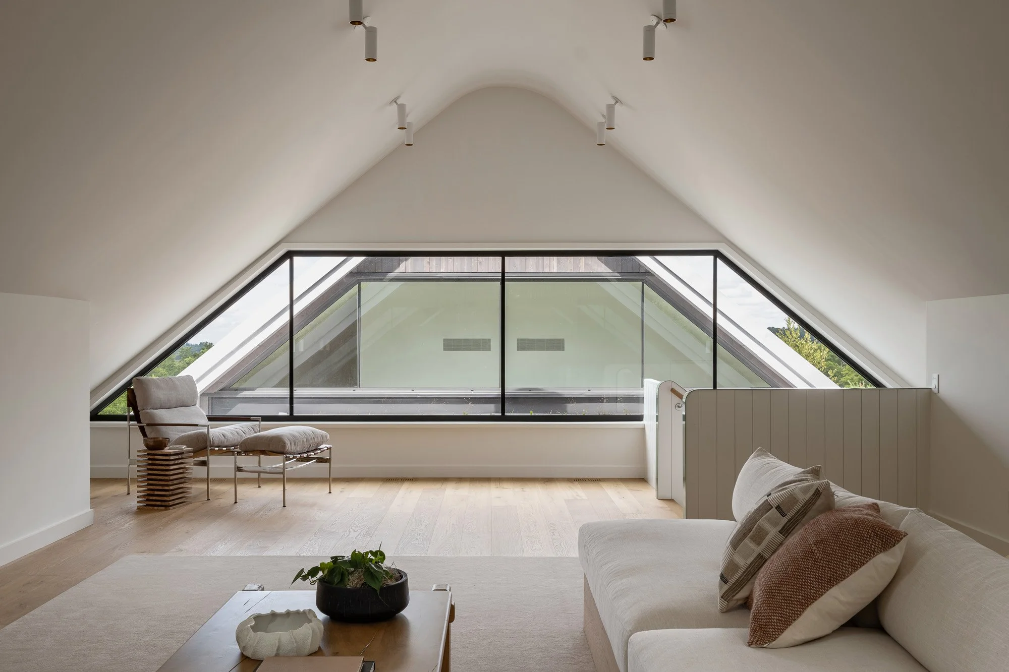 Cozy upstairs family room under a dramatic curved wood vault ceiling looking out onto an eco-friendly green roof.