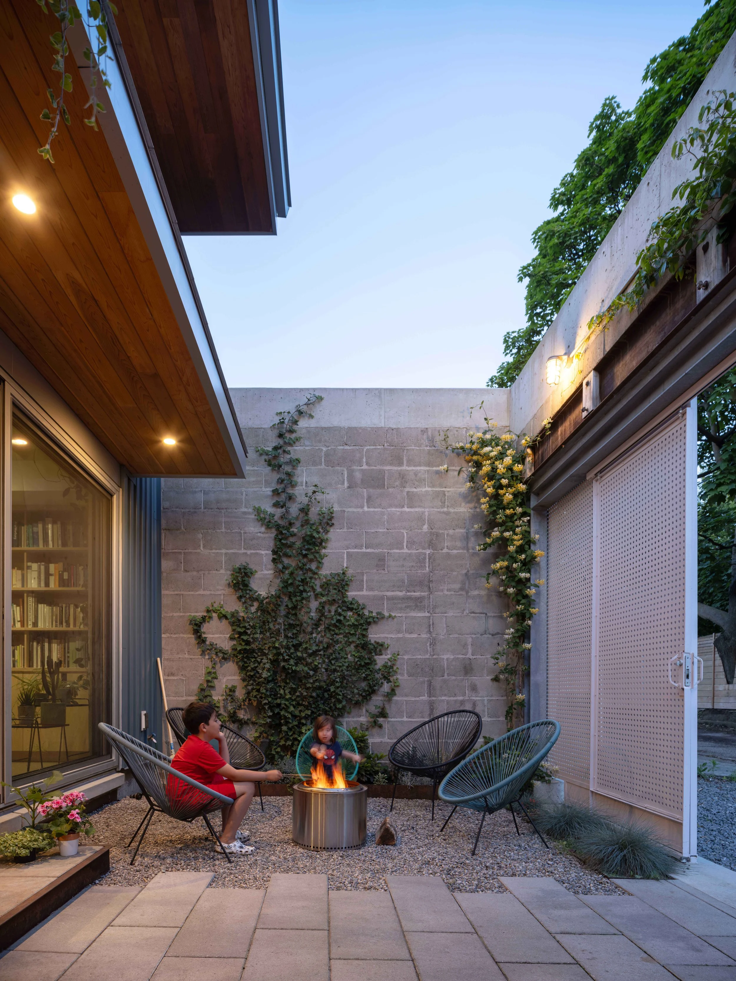 Semi-enclosed internal courtyard utilizing original concrete block warehouse walls paired with perforated sliding privacy screens