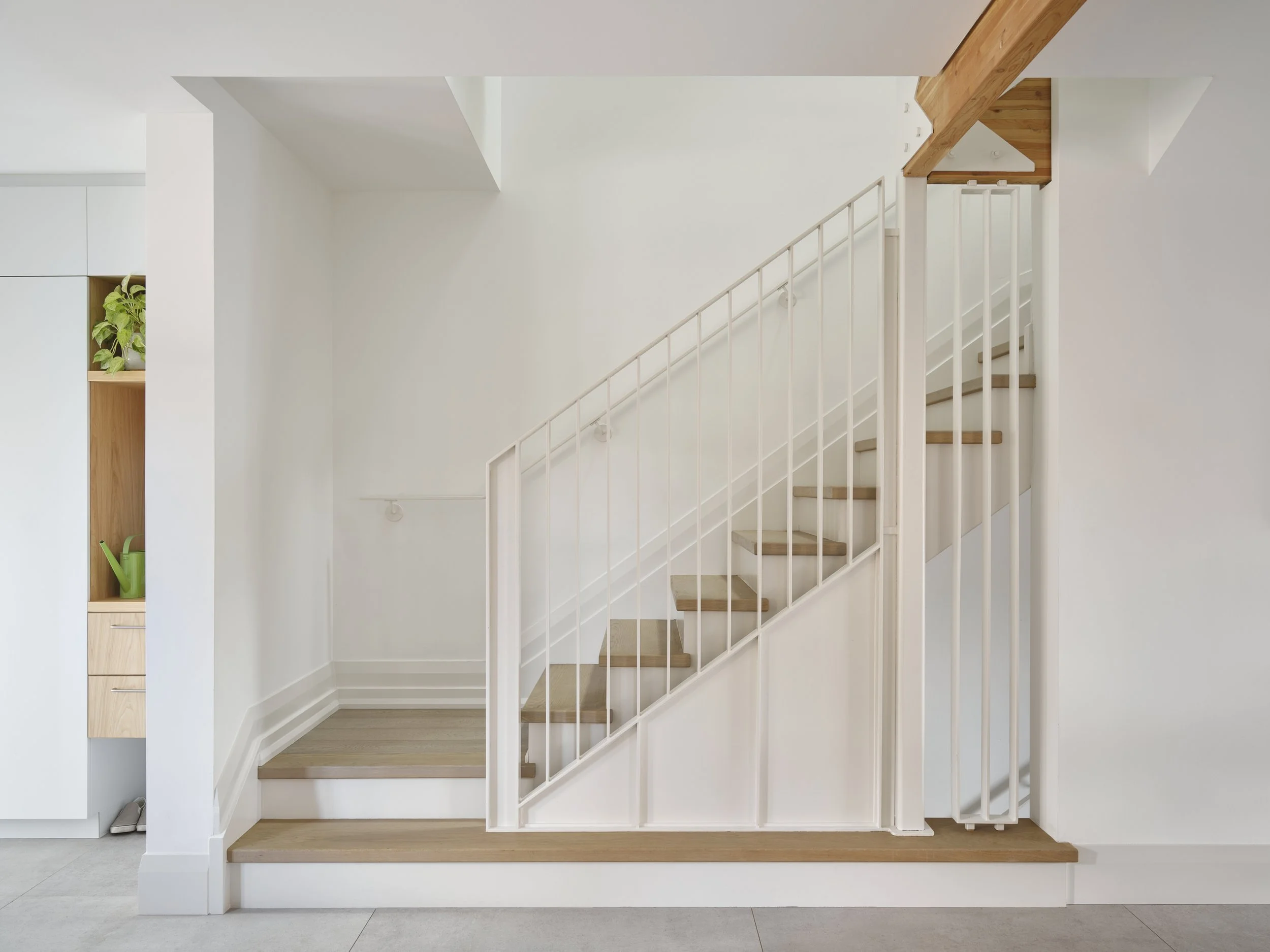 Modern entryway millwork in grey elm with custom steel stair guard by Wayback Architects.