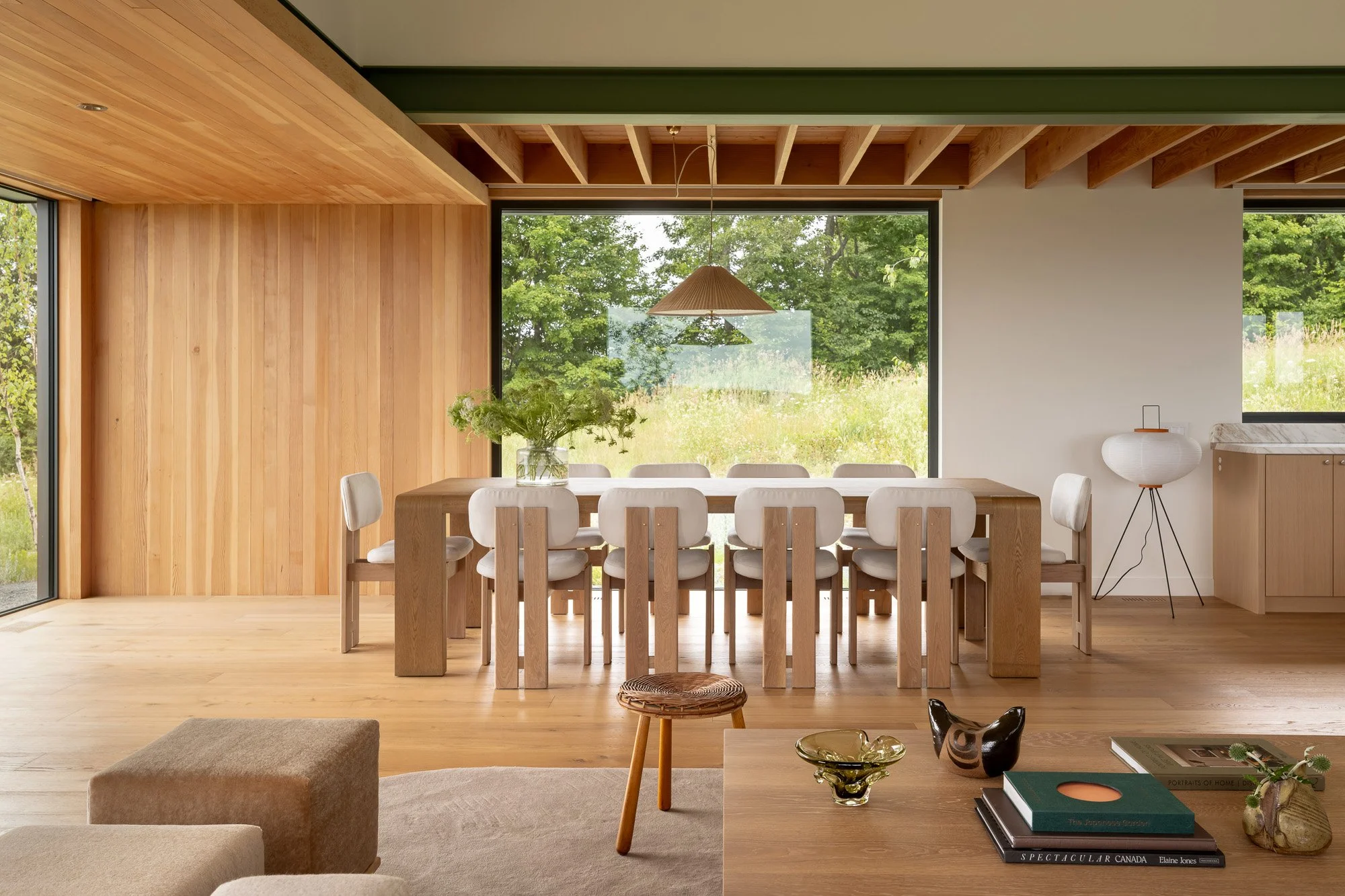 Open-concept modern dining room area inside an expansive great room featuring warm wood accents and large windows.
