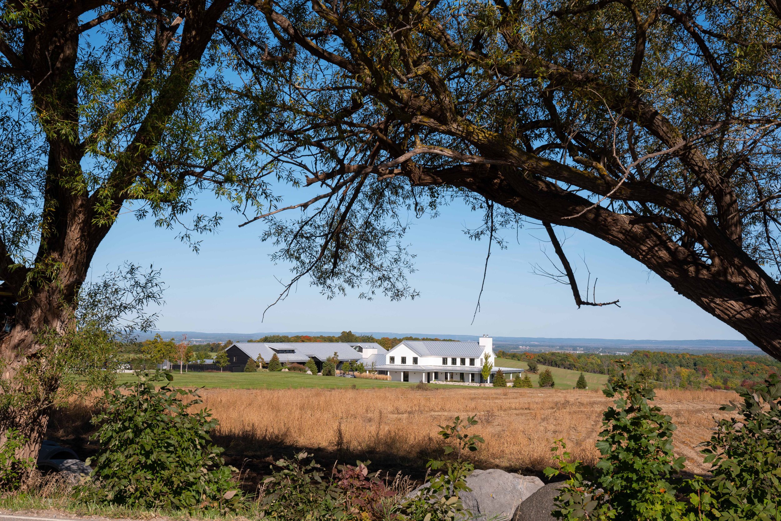 Contemporary rural estate in Creemore showcasing a modern farmhouse silhouette framing distant scenic views of Georgian Bay.