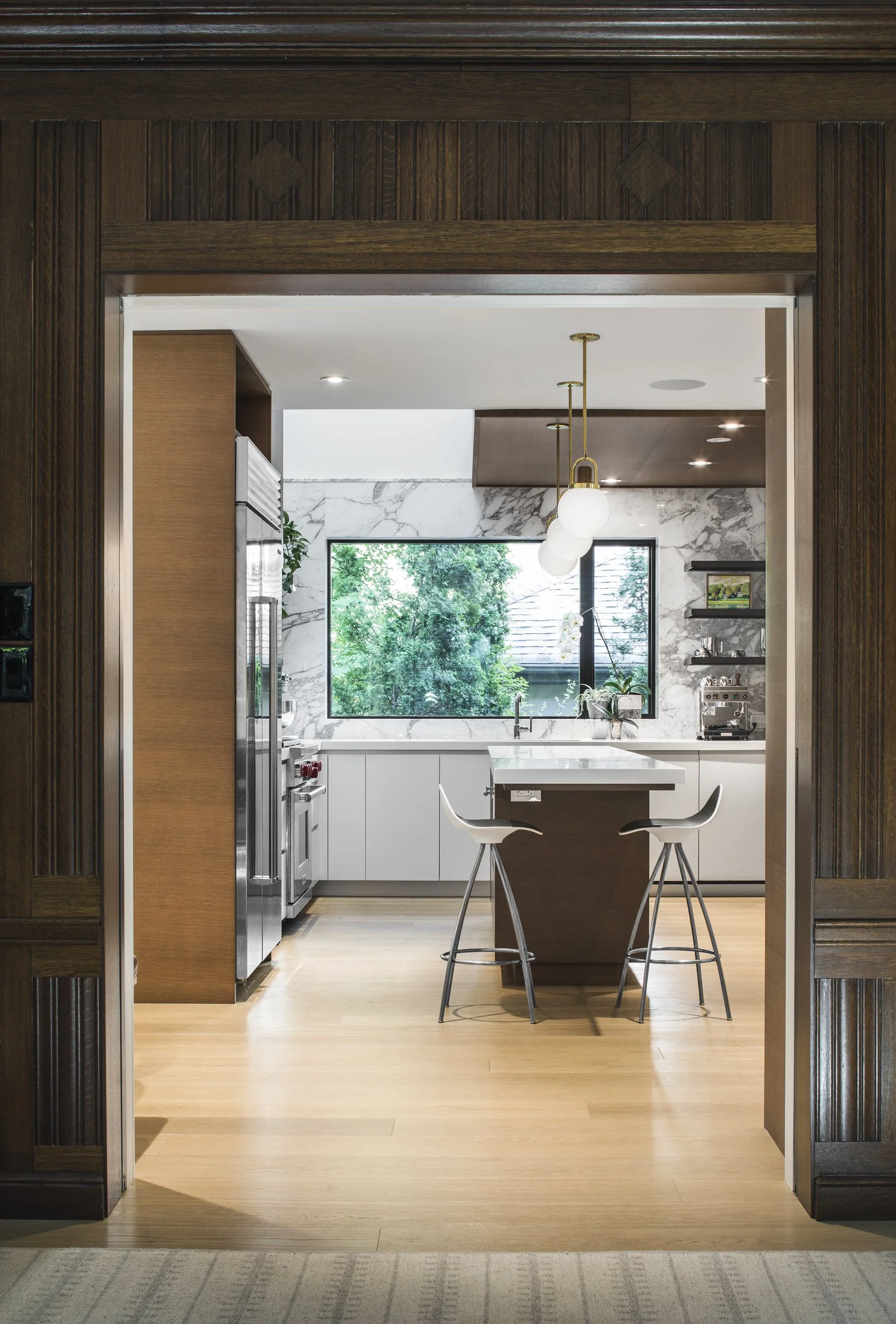 Modern kitchen workspace detail featuring integrated stainless steel appliances, premium marble countertops, and custom millwork.