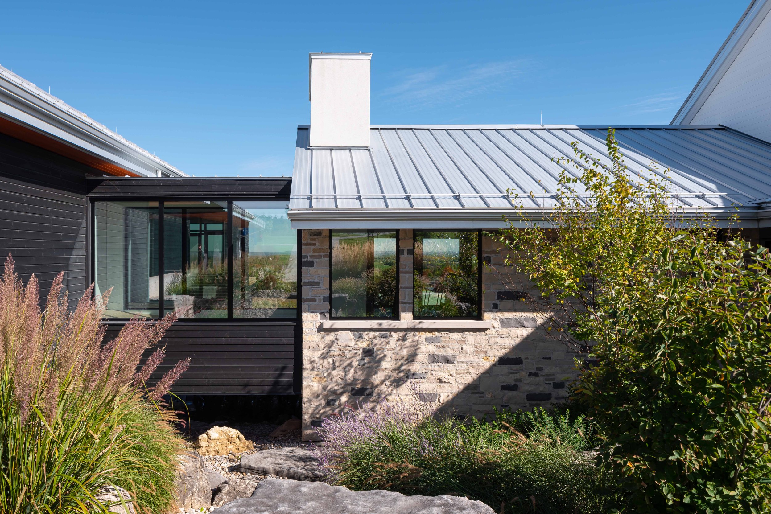 Custom home entryway featuring local stone walls and an architectural dining hall link that integrates with the rural landscape.