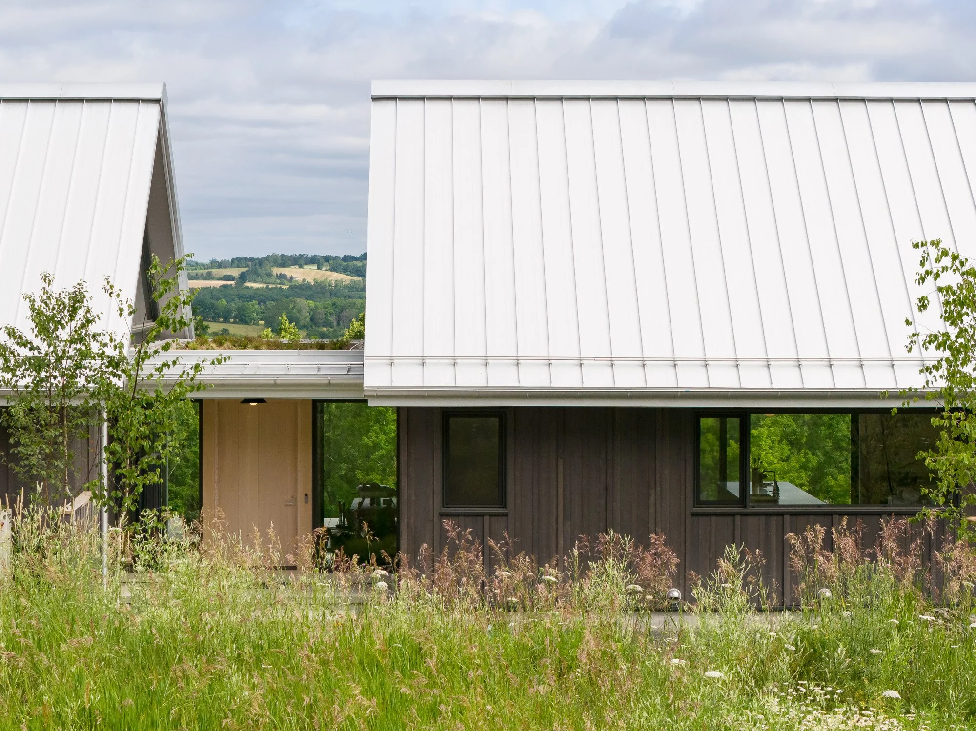 Contemporary Canadian residential architecture showcasing two distinct volumes separated into public and private zones with scenic hilltop views.