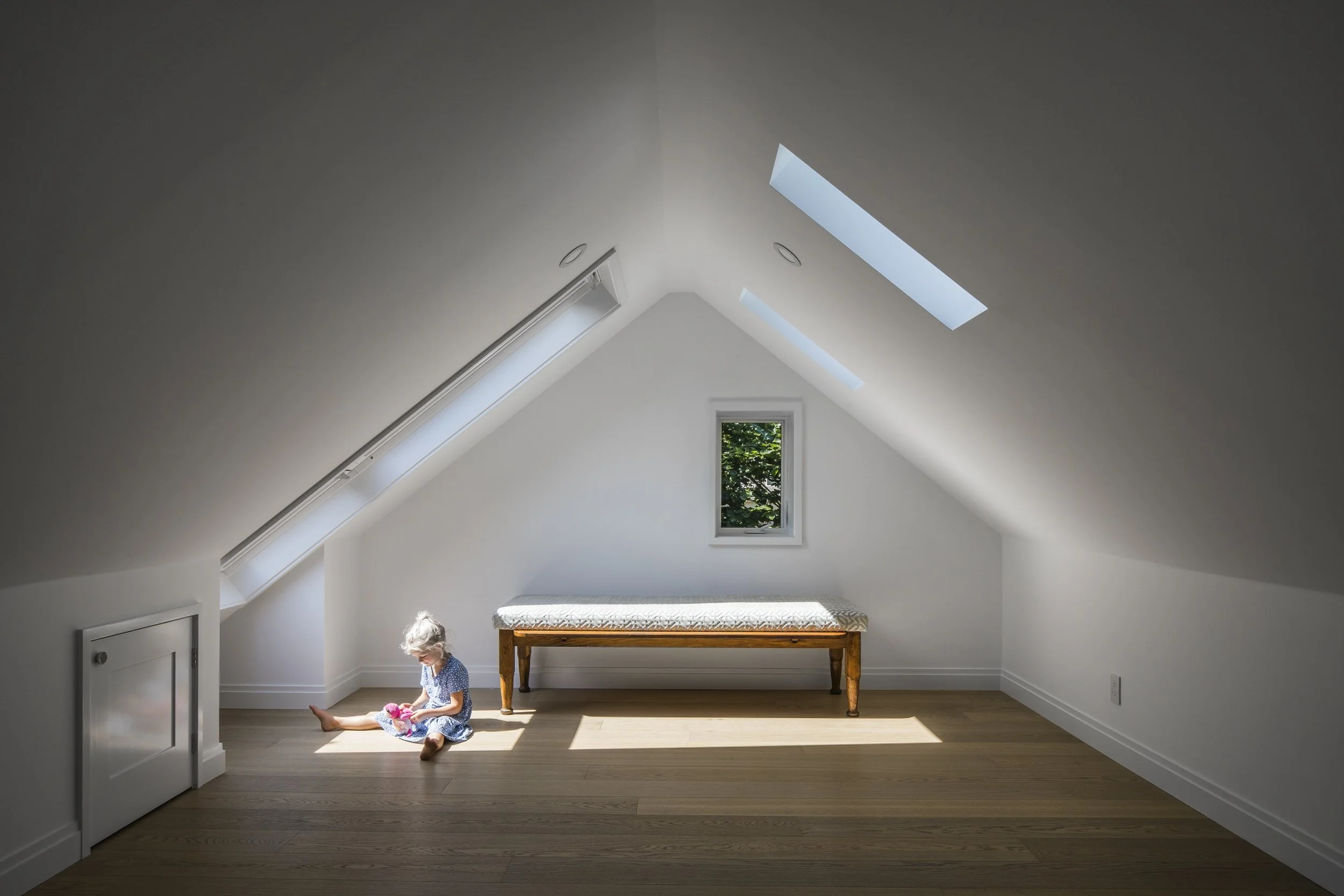 Transformed attic bedroom loft conversion featuring integrated roof skylights and minimalist architectural detailing.
