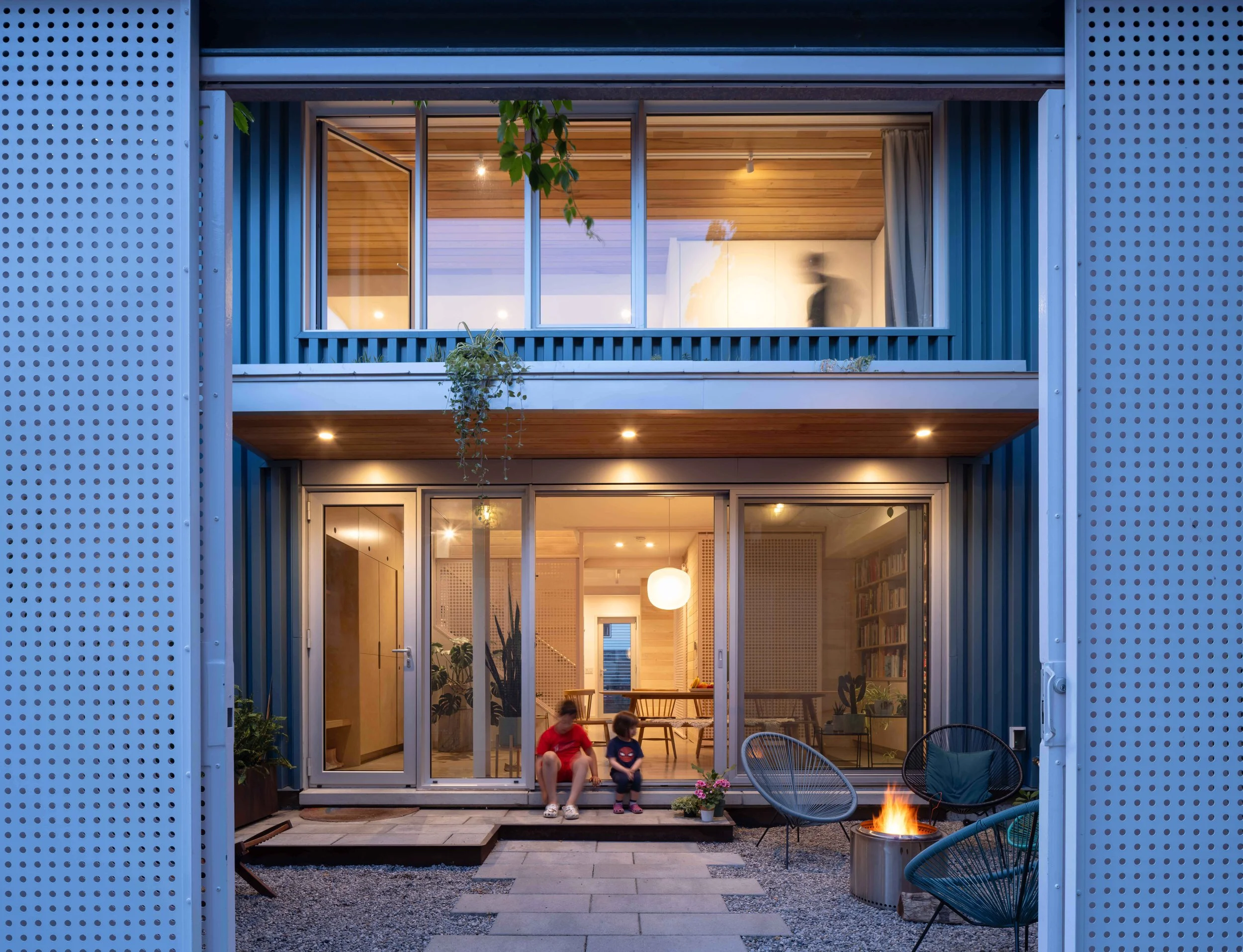 Semi-enclosed internal courtyard utilizing original concrete block warehouse walls paired with perforated sliding privacy screens