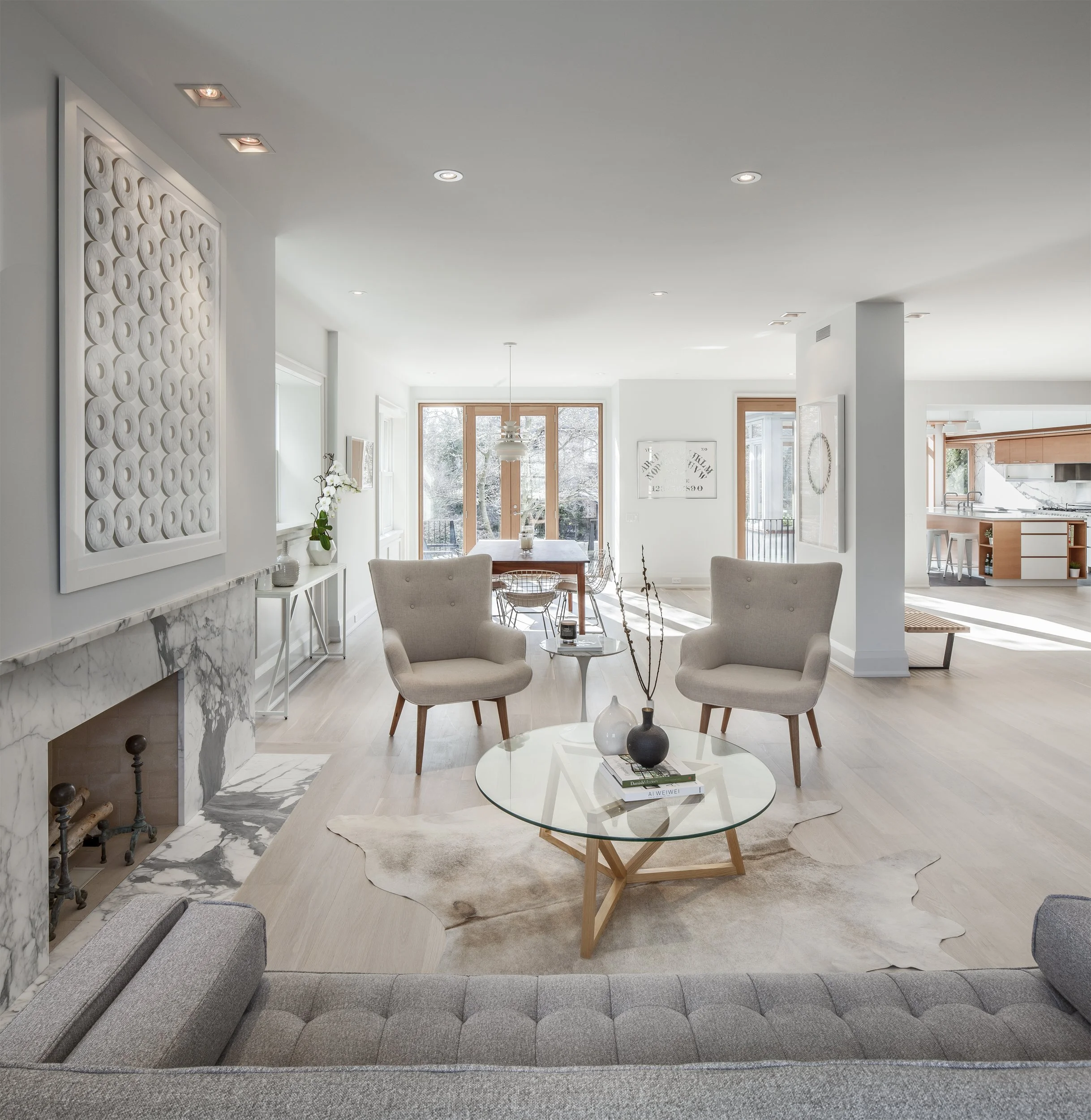 Bright minimalist living room interior design featuring honed natural stone finishes, crisp white walls, and warm custom wood details.