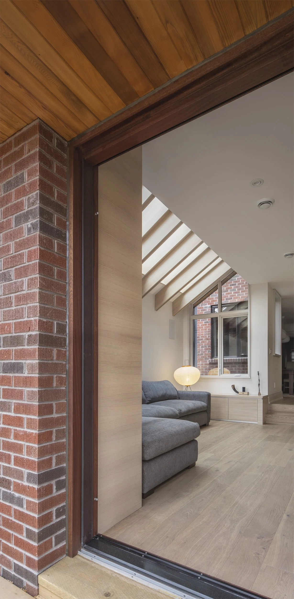 Custom natural cedar wood soffit ceiling detailing looking toward a bright contemporary living room addition with skylights