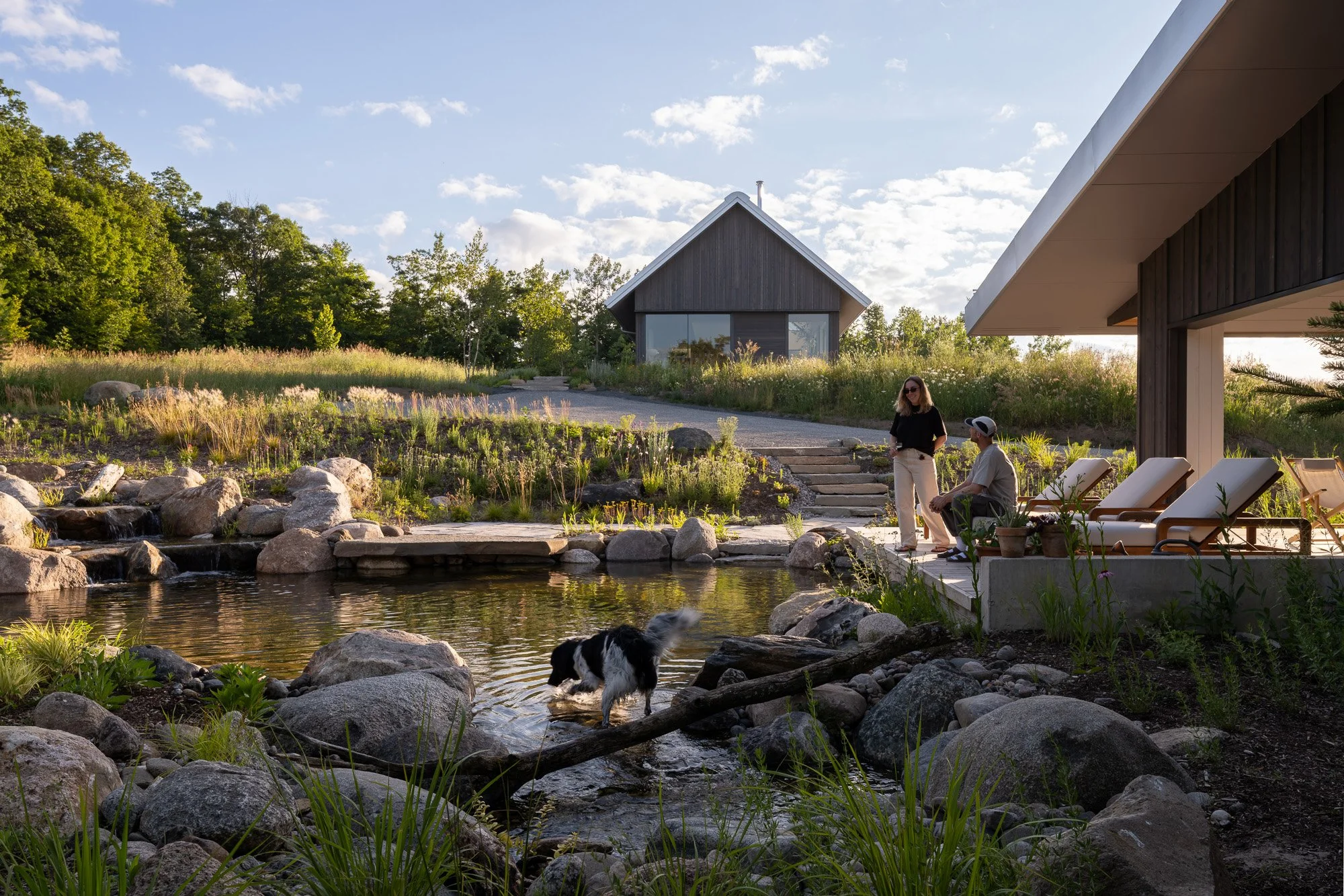 A naturally filtered backyard swim pond and wood-framed pool pavilion nestled into a hillside to protect against wind.