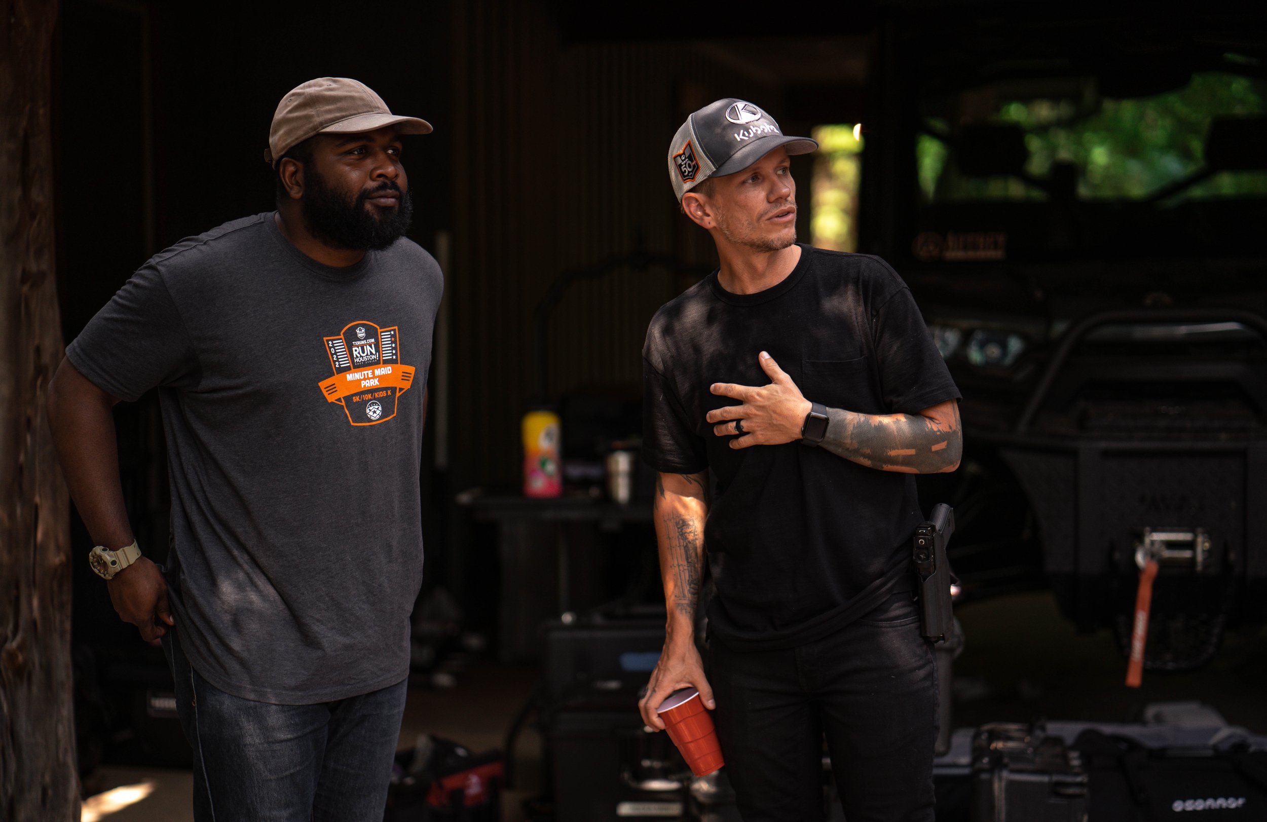 Two crew members discuss a scene inside a dim barn during commercial film production.