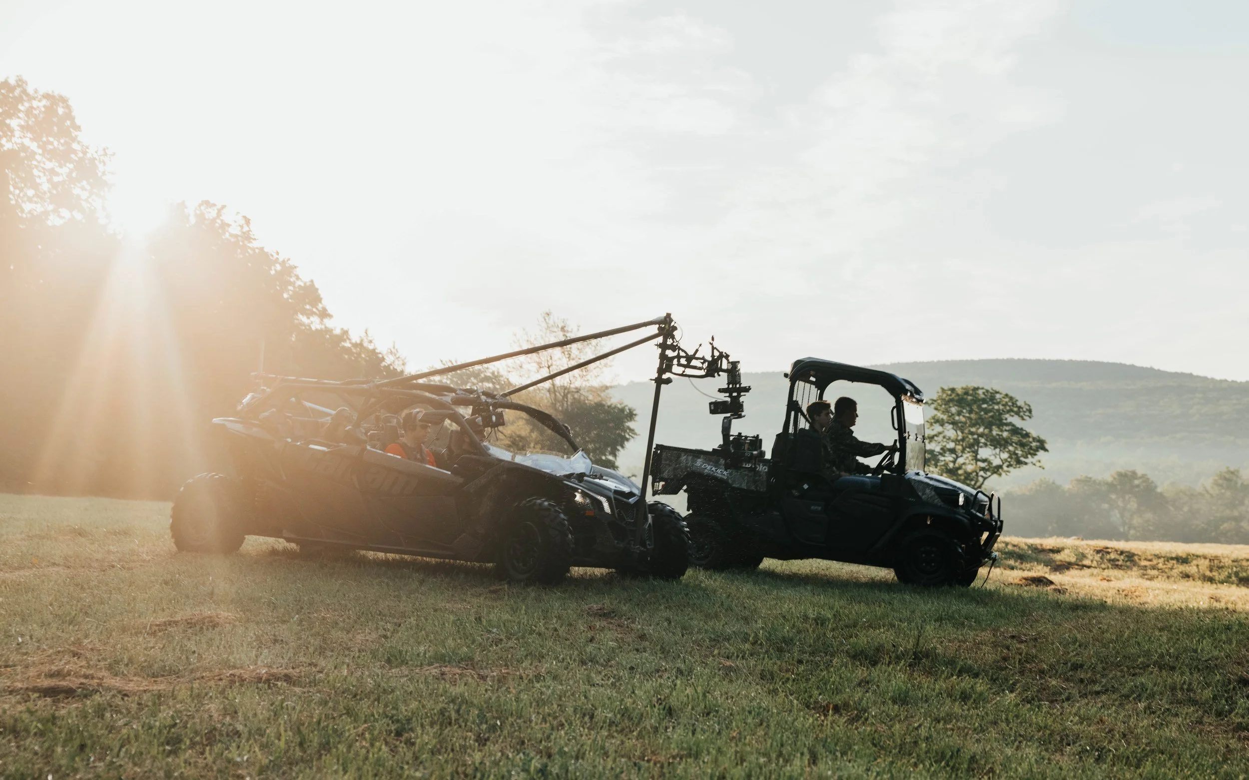 A utility vehicle crosses a pasture at sunset in a cinematic agriculture video production scene.