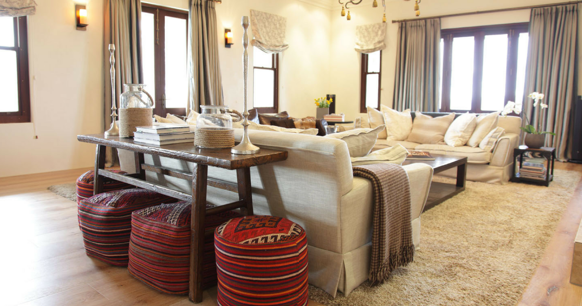 A light-filled open lounge space is made cozy by oversized cushions, woollen throws and unique, brightly coloured ottomans.&nbsp;