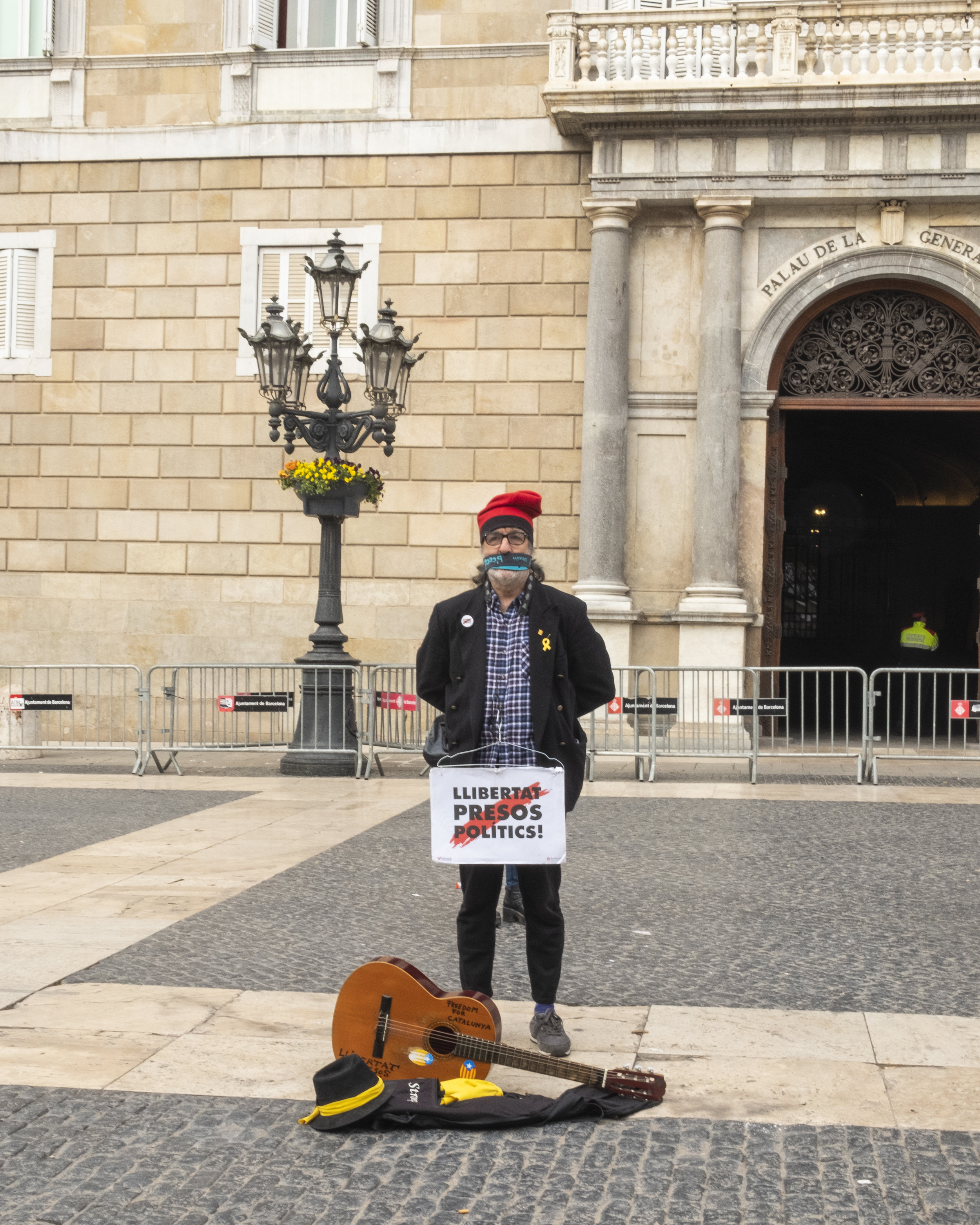  Catalan nationalists protest for independence from Spain. This man stands in a populated city square, silently demanding freedom as indicated by his yellow ribbon and sign which translates to “freedom of political prisoners. These high-ranking Catal