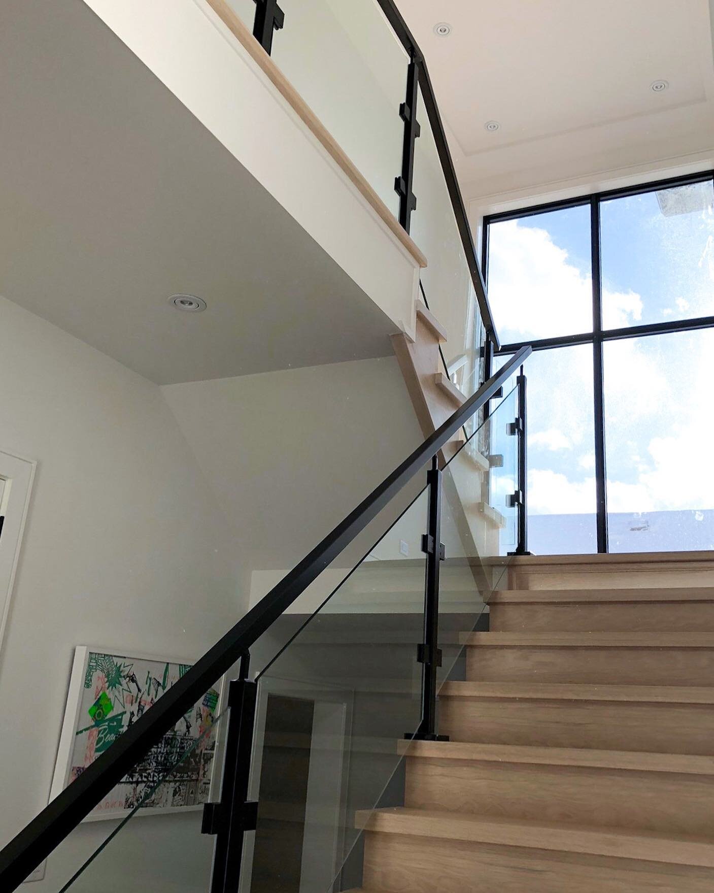 Modern staircase, glass railings and blue skies! ☁️💙

 #ossingtonhomes #designbuild #torontobuilder #glassrailings #stairs