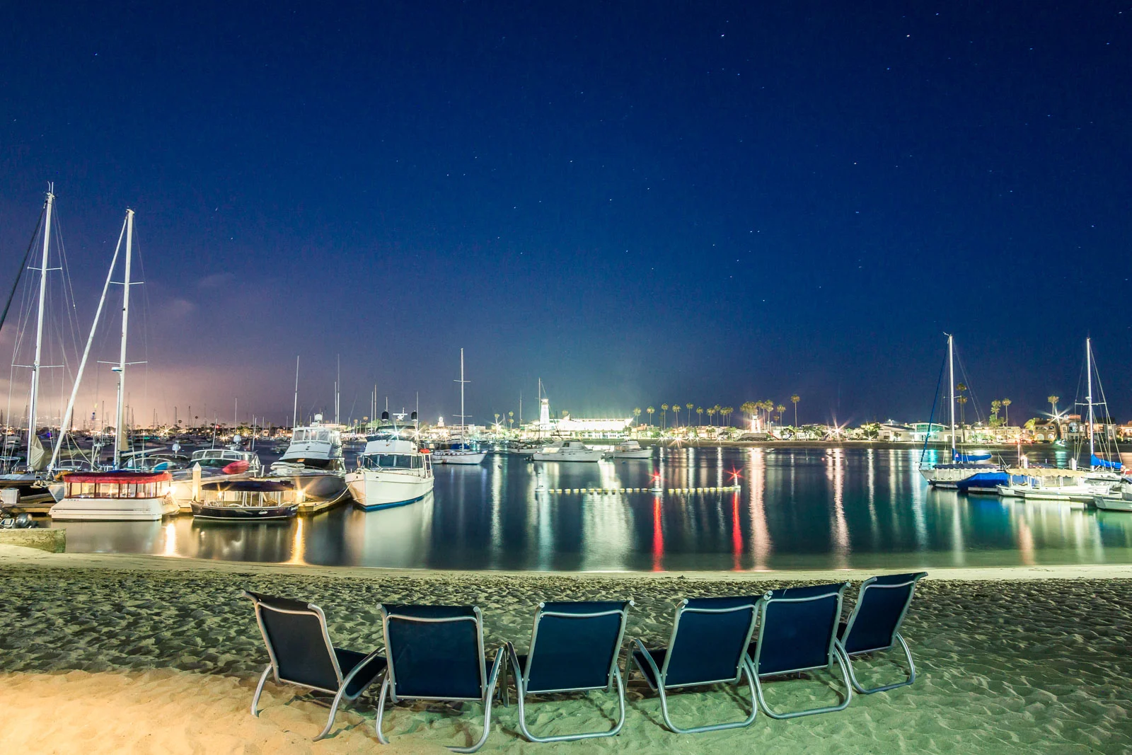 Lido Island beach With a view of the harborIlluminated at night with palm trees and lounge chairs