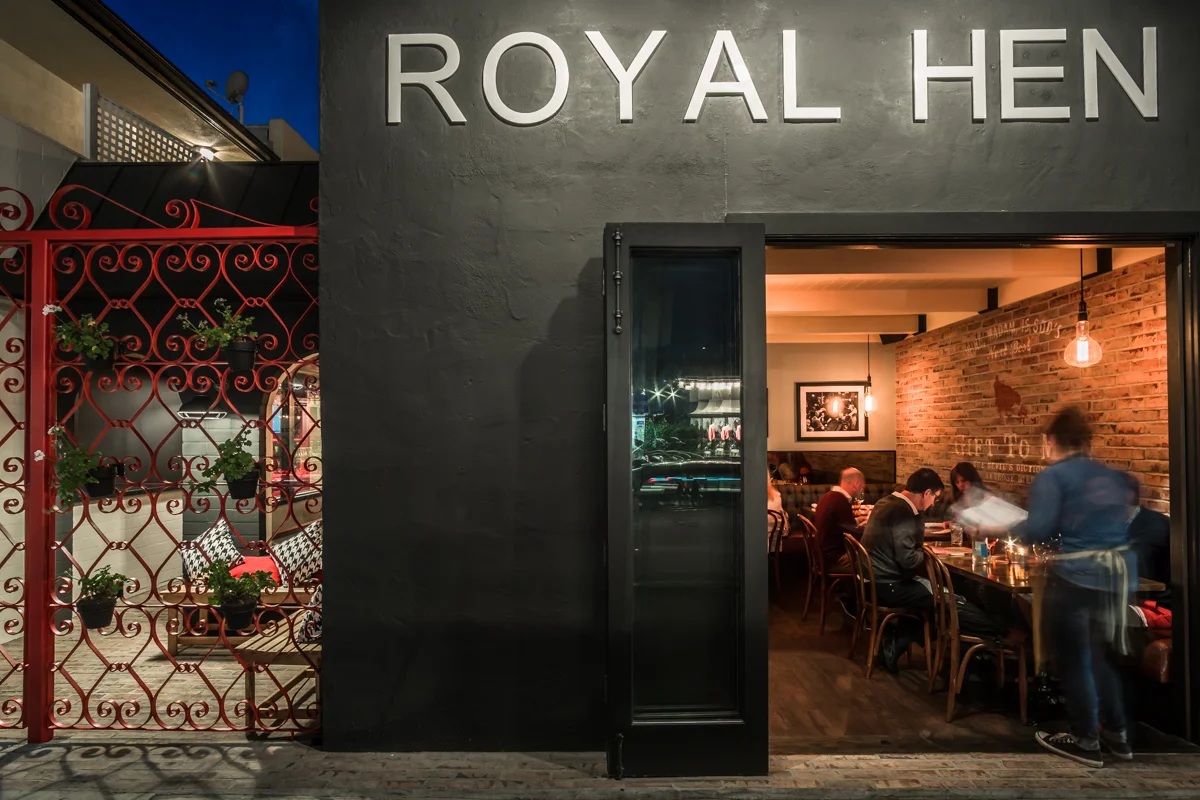 Exterior photograph of the front of the royal hen restaurant in Balboa Island at nighttime
