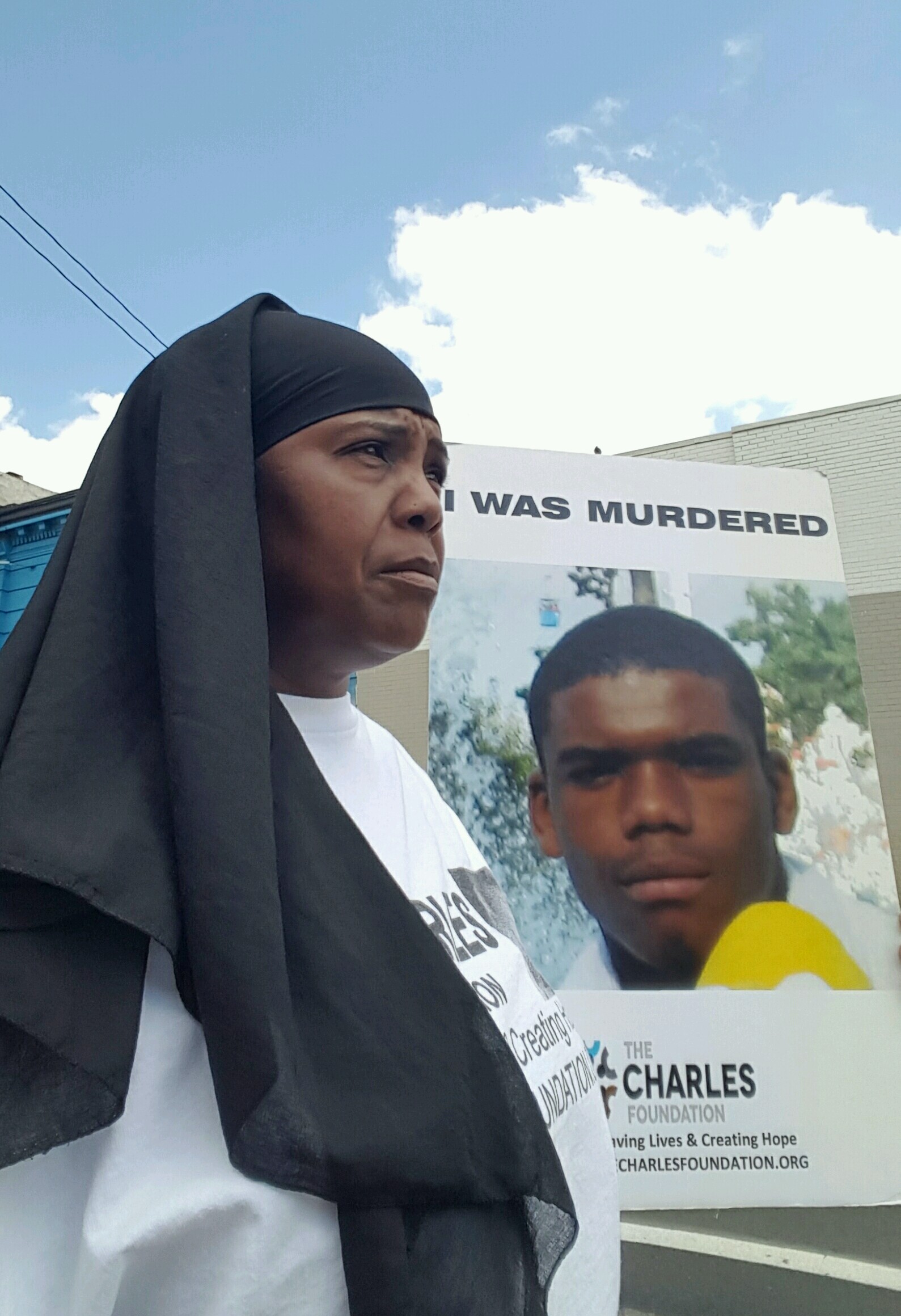 The Founder of The CHARLES Foundation, Movita Johnson-Harrell, with a poster of Charles Johnson 