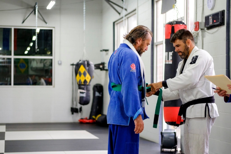 Photo Cred: Joed Viera Professor Josh Ketry fastens a green belt on me at BUMA .