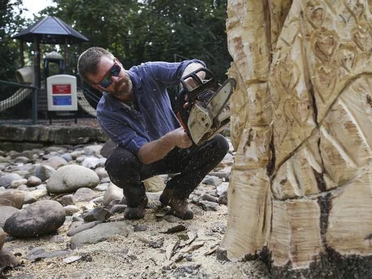 Artist Joe Autry at work carving the totem pole from a tree brought down by storms.