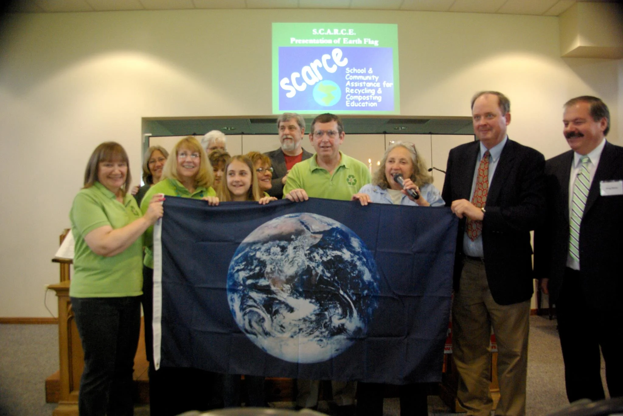 The Green Disciples of the First United Methodist Church of West Chicago accept the Earth Flag from Kay McKeen of S.C.A.R.C.E