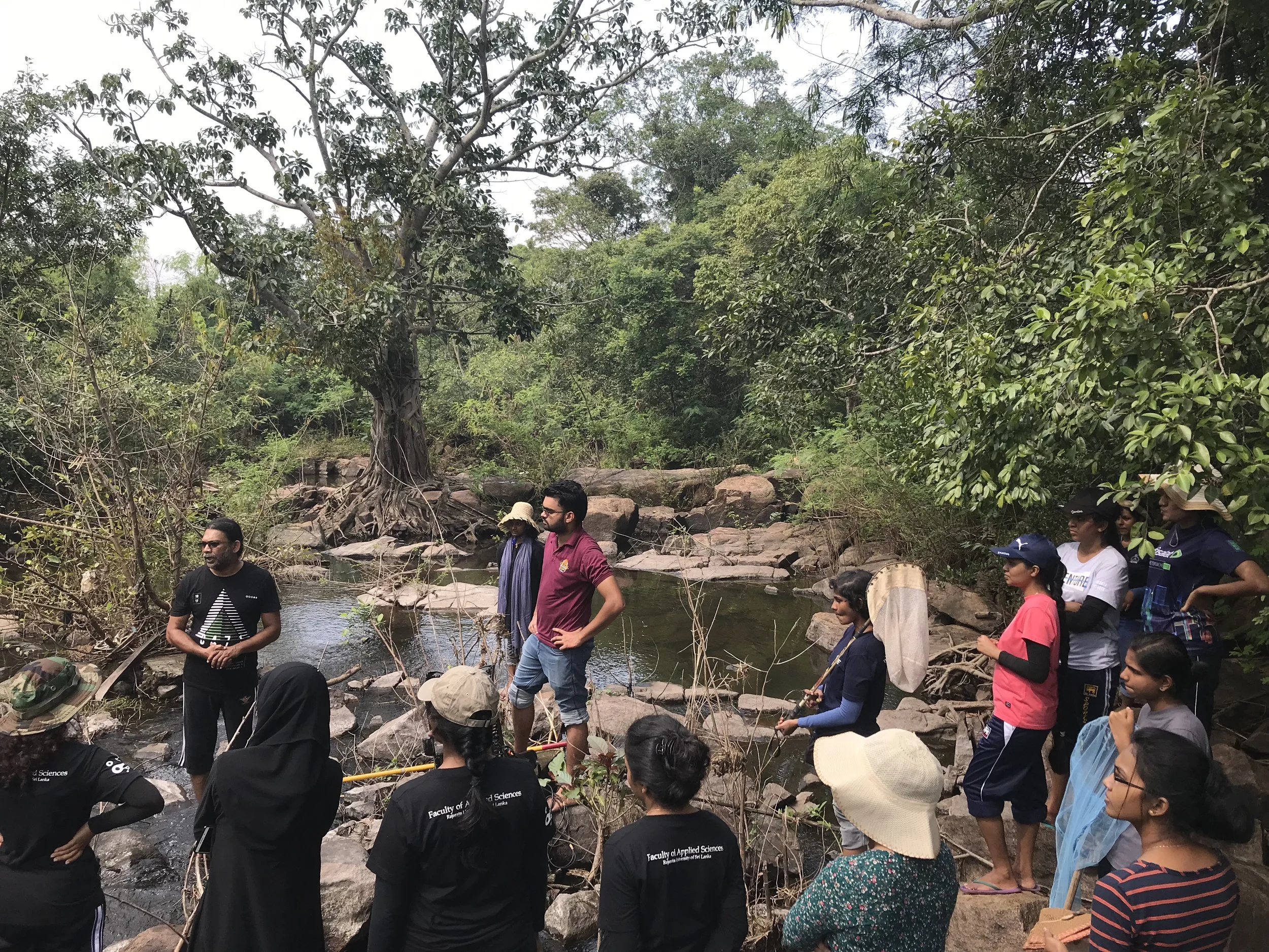 Undegraduate students from Rajarata University listening to the day’s plan from their instructor, moments before they all enter this stream to begin sampling for various aquatic creatures.