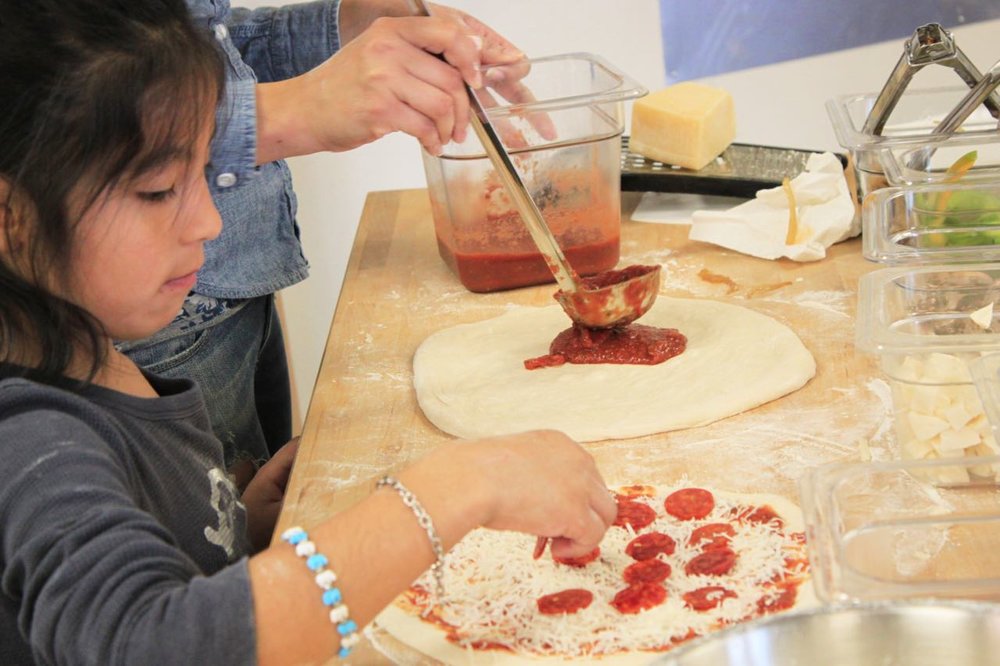 Young girl making pizzas.