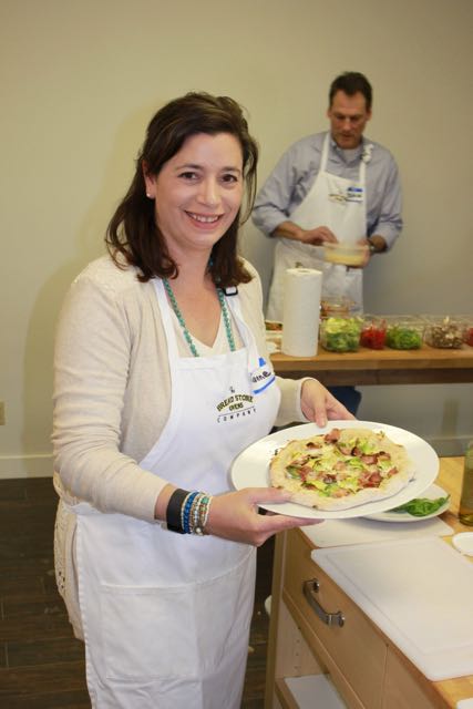 Woman holding a baked pizza.