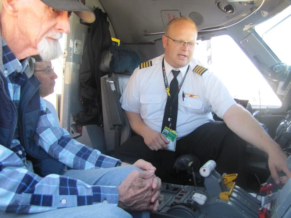 Bill Havener (left), Airport Hall of Fame Member, and Craig Woodley of Woodley Aerial Spray , look on as ExpressJet Airlines Chief Pilot of Chicago O'hare Domicile, Captain Drew Wilkens, explains some features of the Embraer 145 passenger jet during the 2017 Aviation Career Day and Airport Open House.