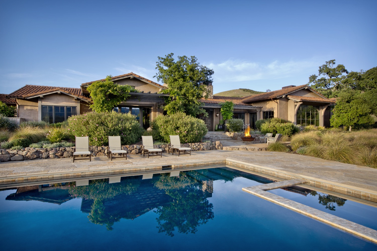 The pool reflects the blue sky, and the firepit was made from a reclaimed sugar bowl.
