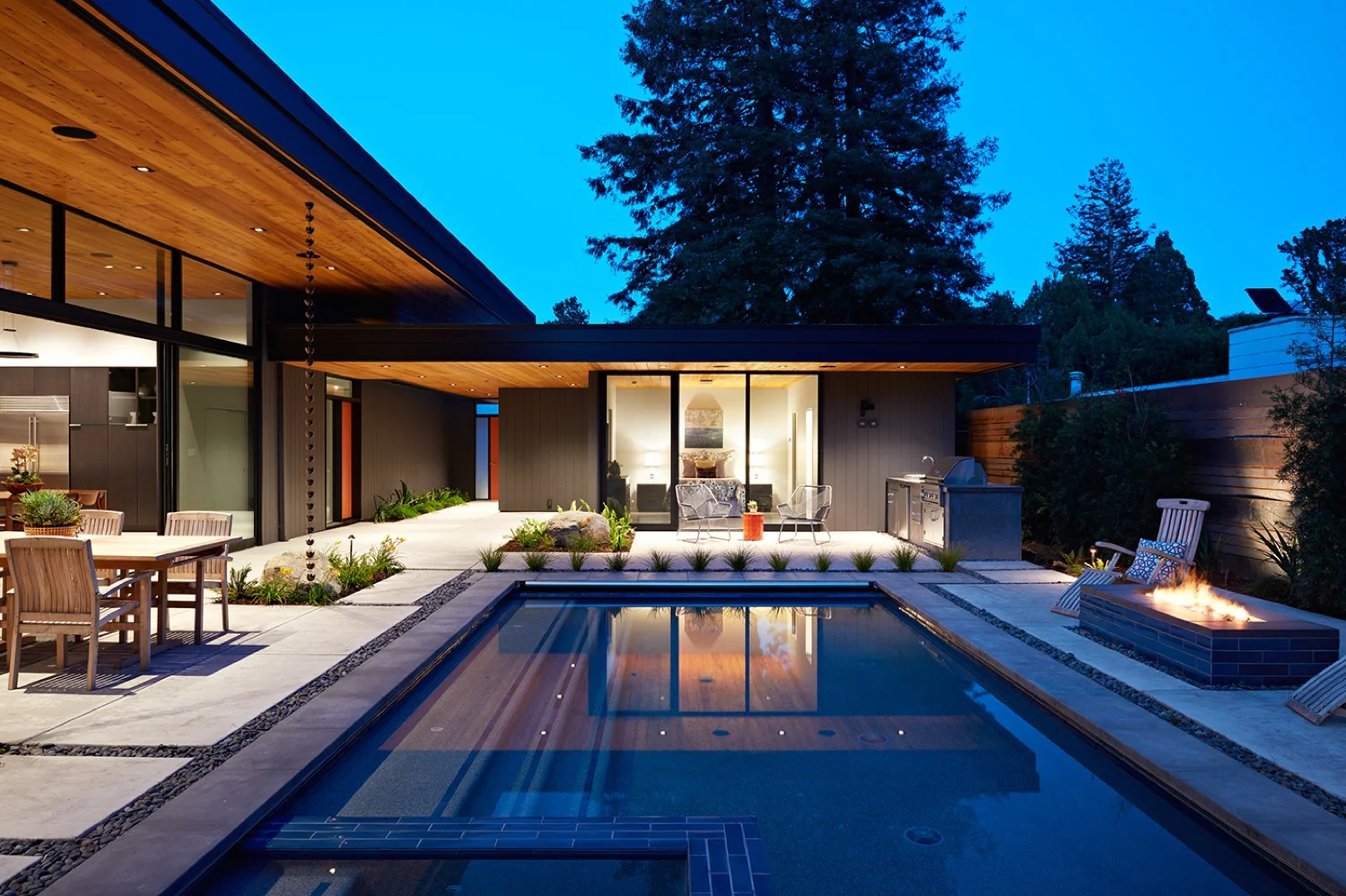The metal fence extends to behind the outdoor kitchen near the guest room.