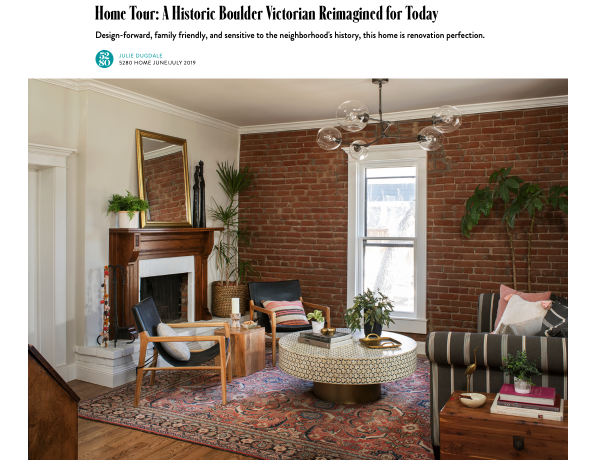 Saltwolf designed living room with brick wall, mid-century modern furniture, a fireplace with a mirror and plants, a round coffee table, and a patterned rug from an article in Colorado Homes Magazine.
