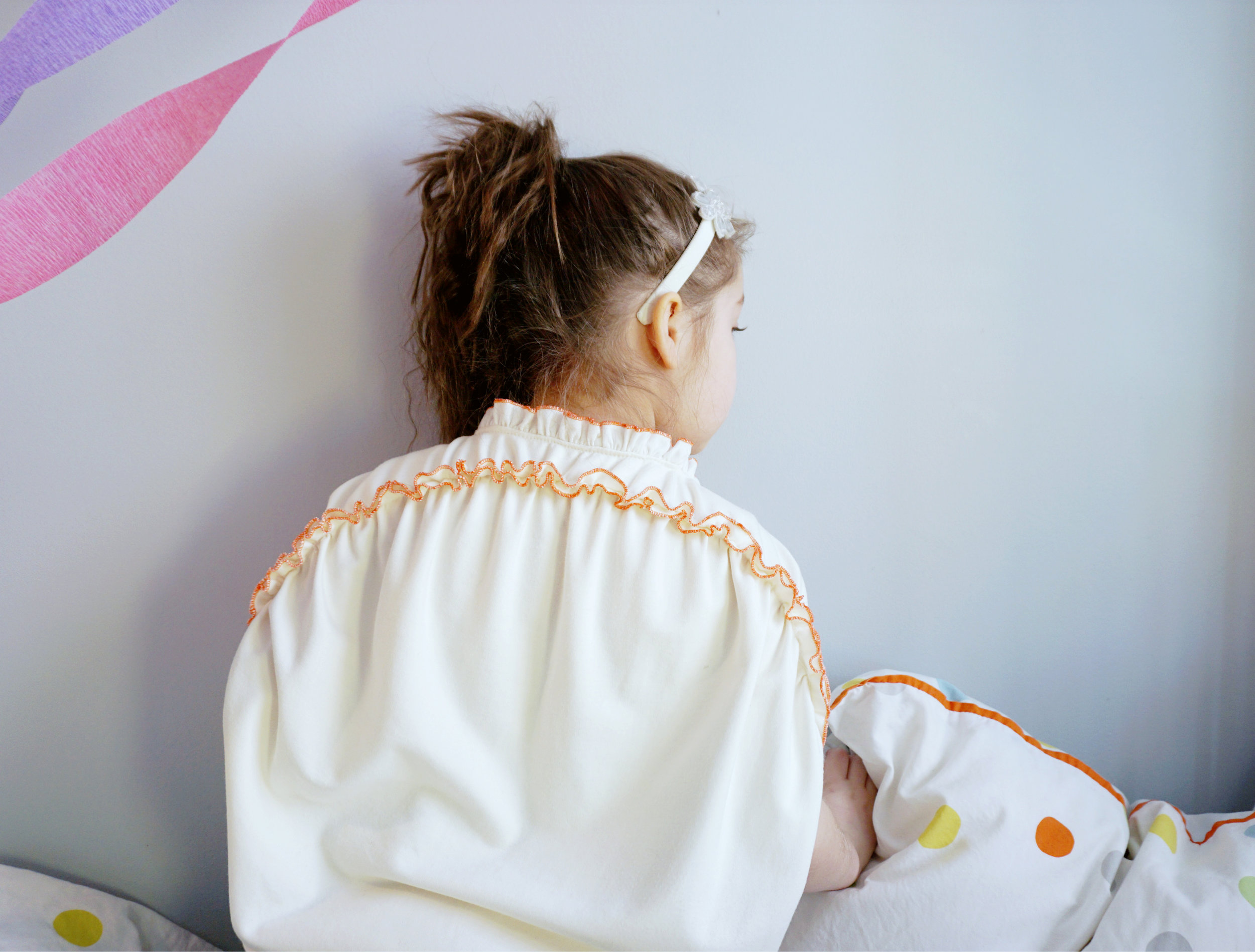 The gathering on the back of the child garment is a symbol of cake frosting. It also means cheesecake to Teasy is something that brings everyone in the family together. (aka gathering)