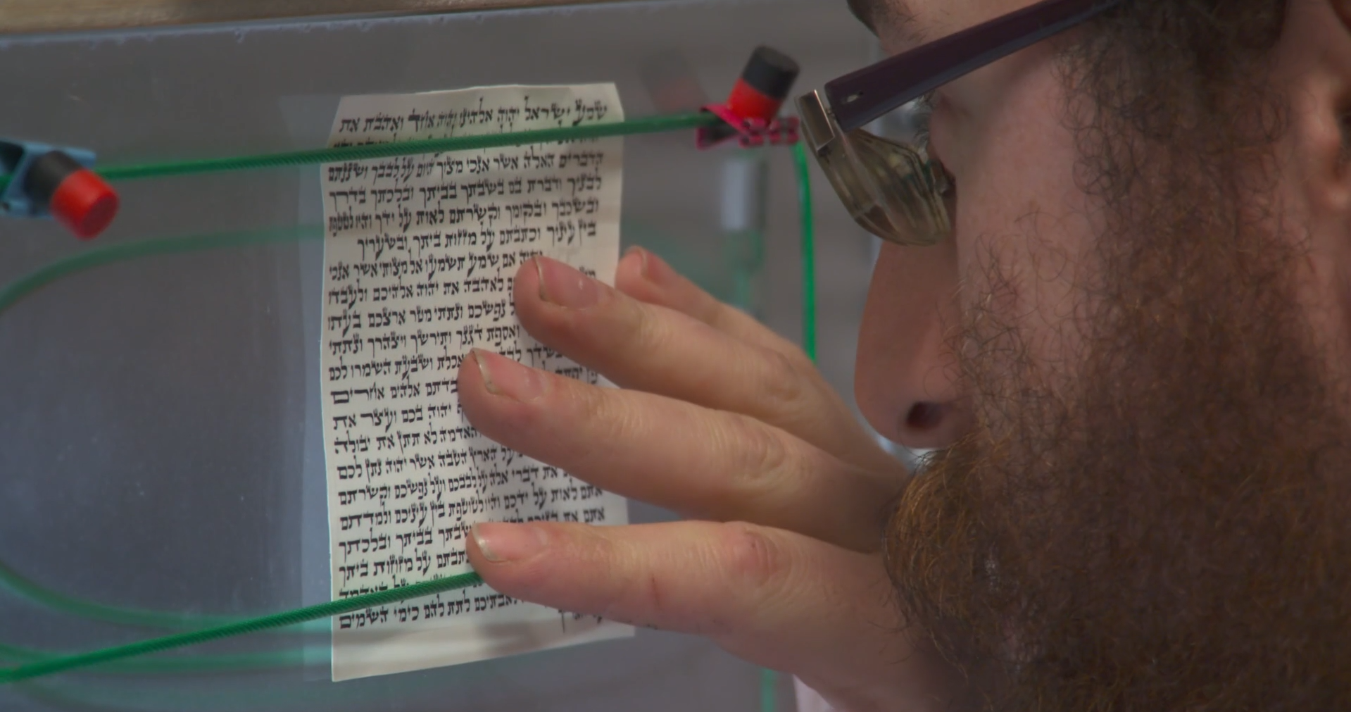 A scribe inspects a Mezuzah scroll