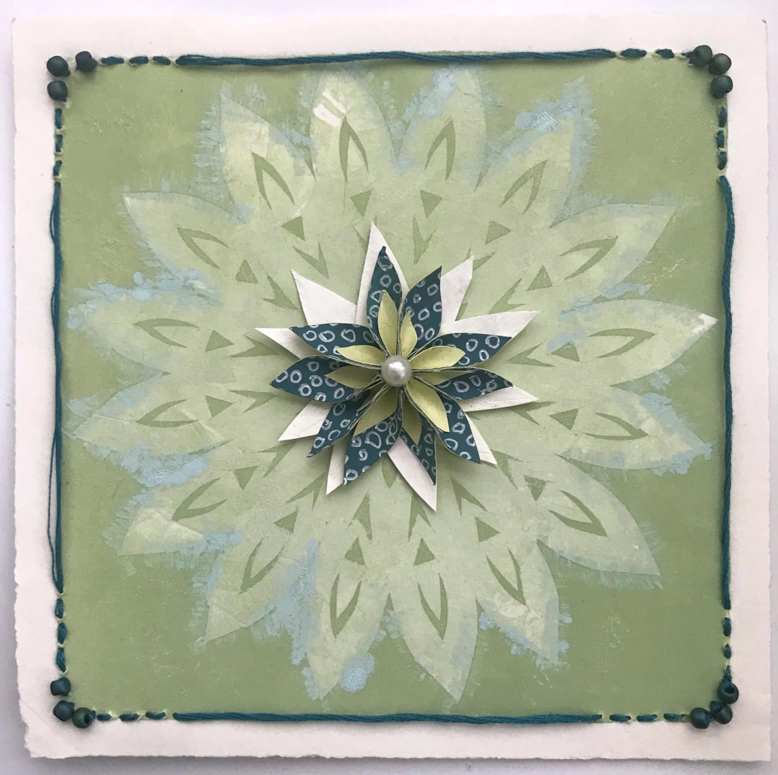 Some recent personal work is taking monoprints from a few years ago and collaging paper flowers, stitching, beads and embellishments to them. The result combines my loves of printmaking, bling, and paper arts. It’s a fine line between craft and art in my world.