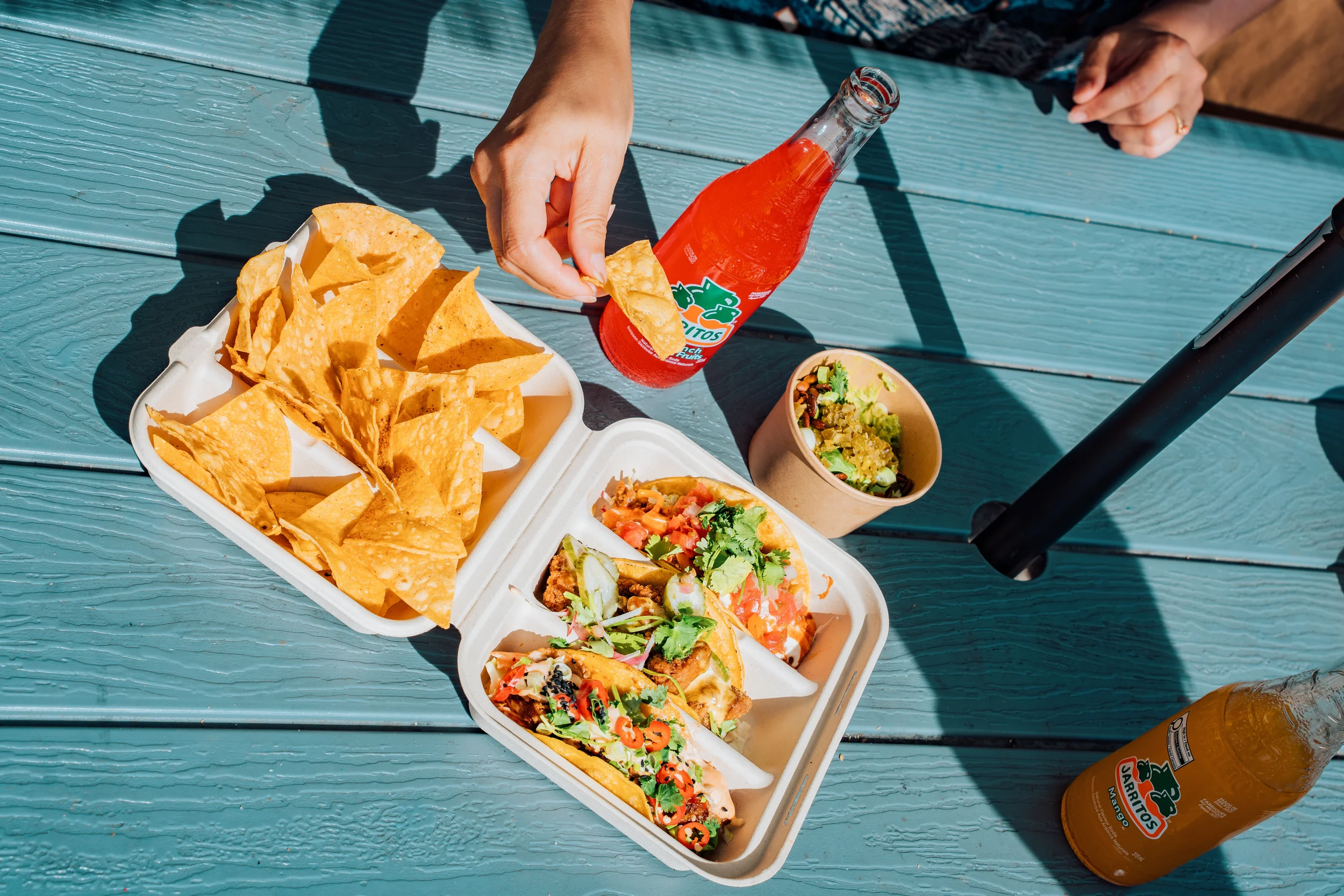 Take-out tacos, guacamole dip and Jarritos on a bench table in Westdale Hamilton near McMaster University