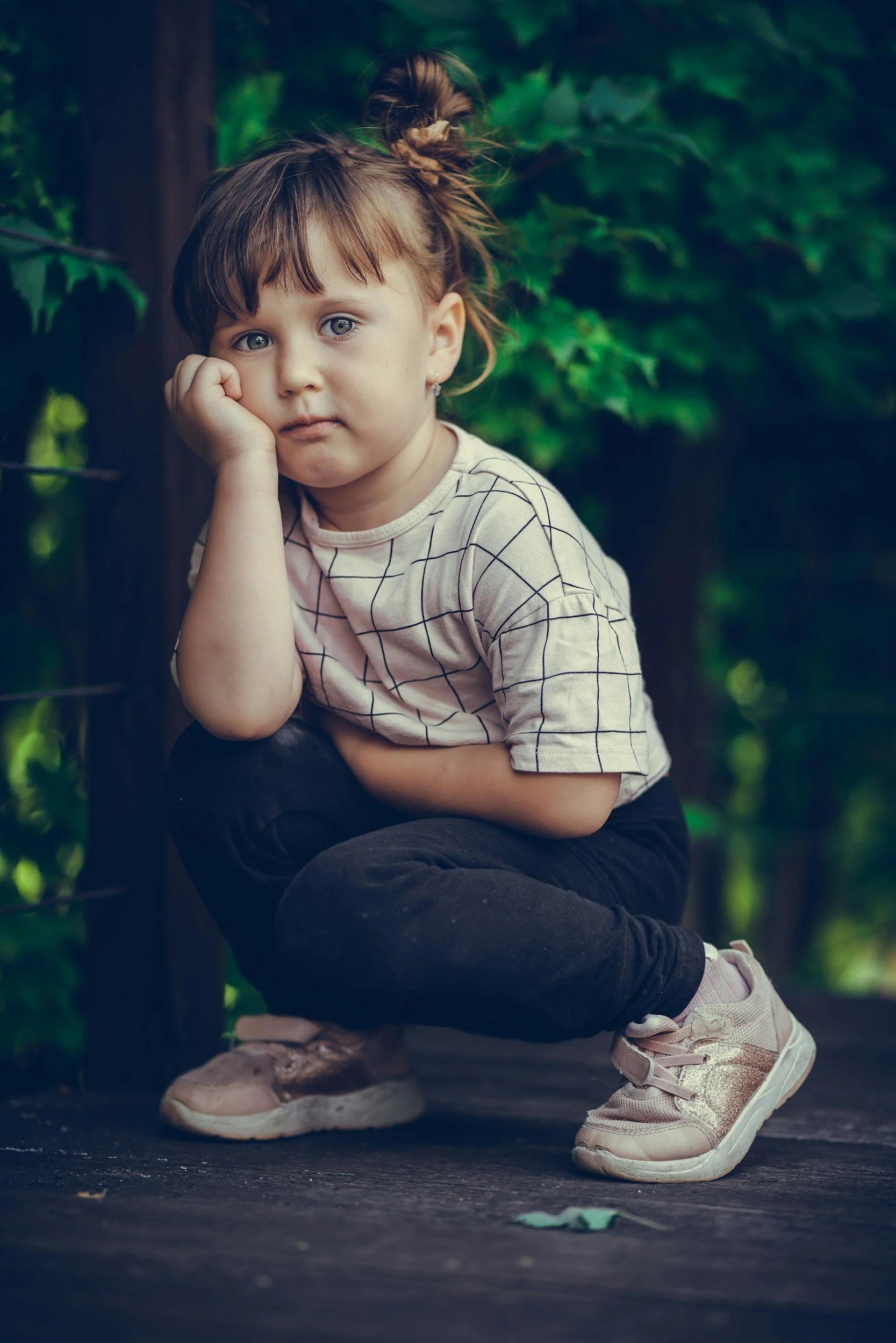 Girl sitting down with hand rested on her face, as she seems physically stressed
