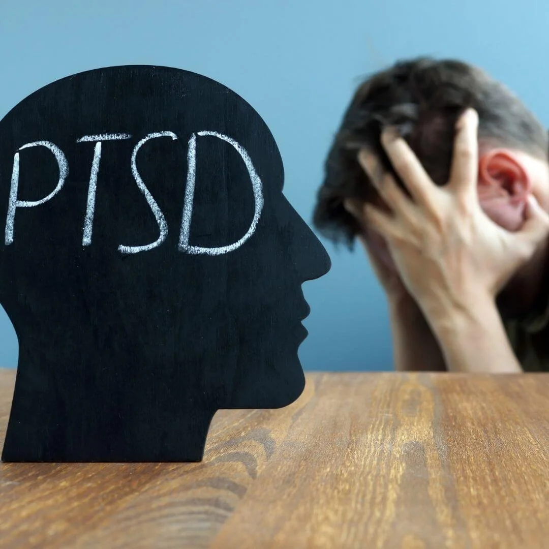 PTSD word with person with hands holding up head.