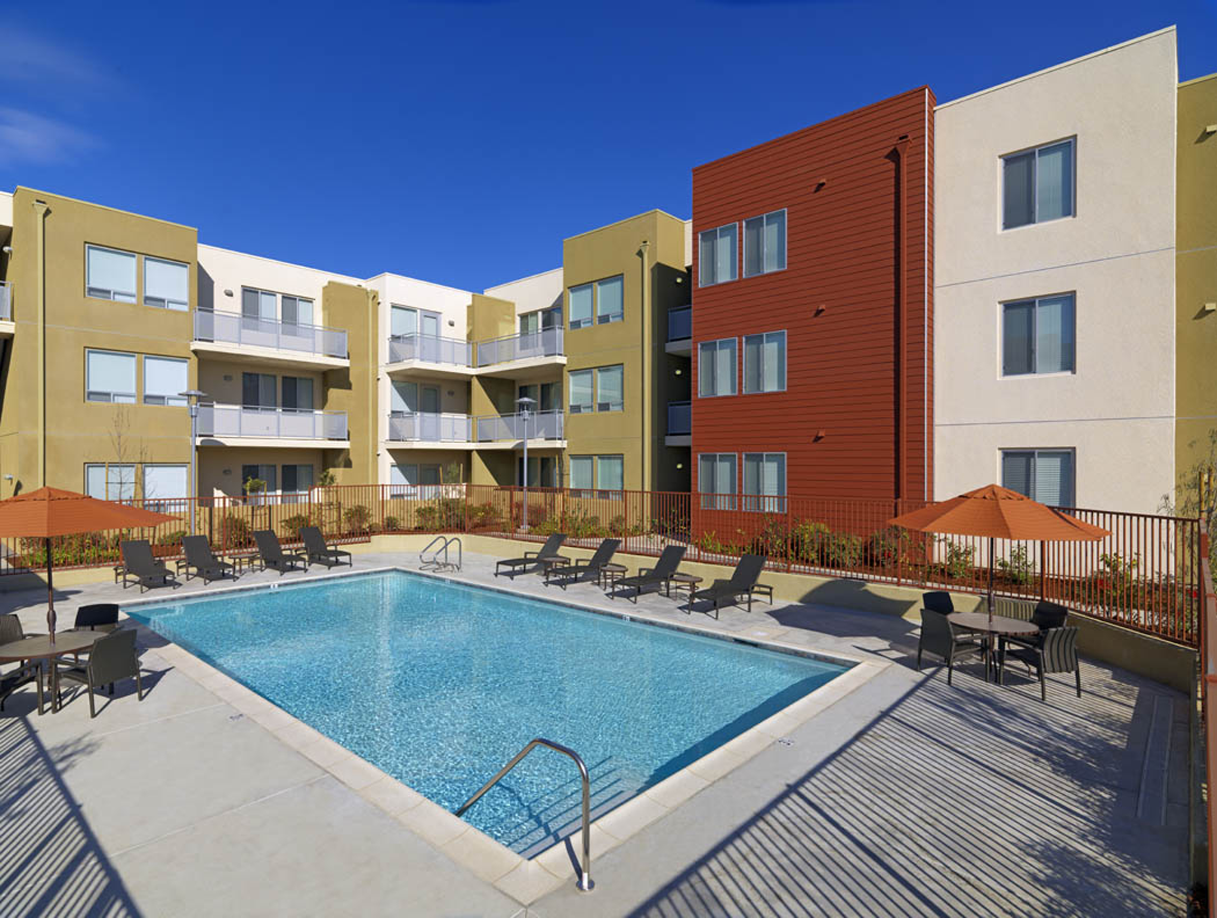 Gated pool and communal chairs in courtyard at Vista Del Cielo Family Housing development