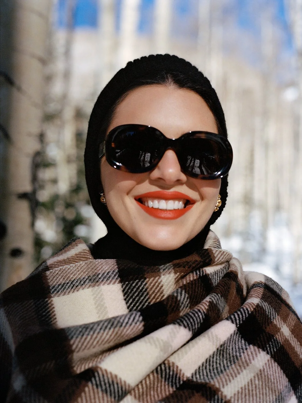  Close portrait of Kendall Jenner in dark sunglasses and a checked winter scarf in Aspen for FWRD, photographed by Sean Thomas. 
