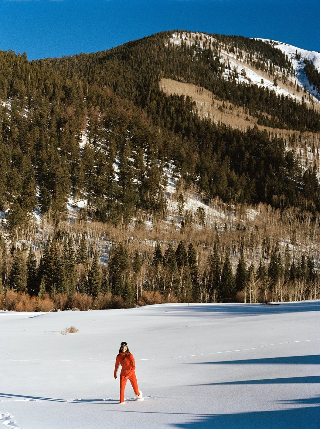  Kendall Jenner in a red ski suit crossing an open snowfield beneath the Aspen mountains for FWRD, photographed by Sean Thomas. 