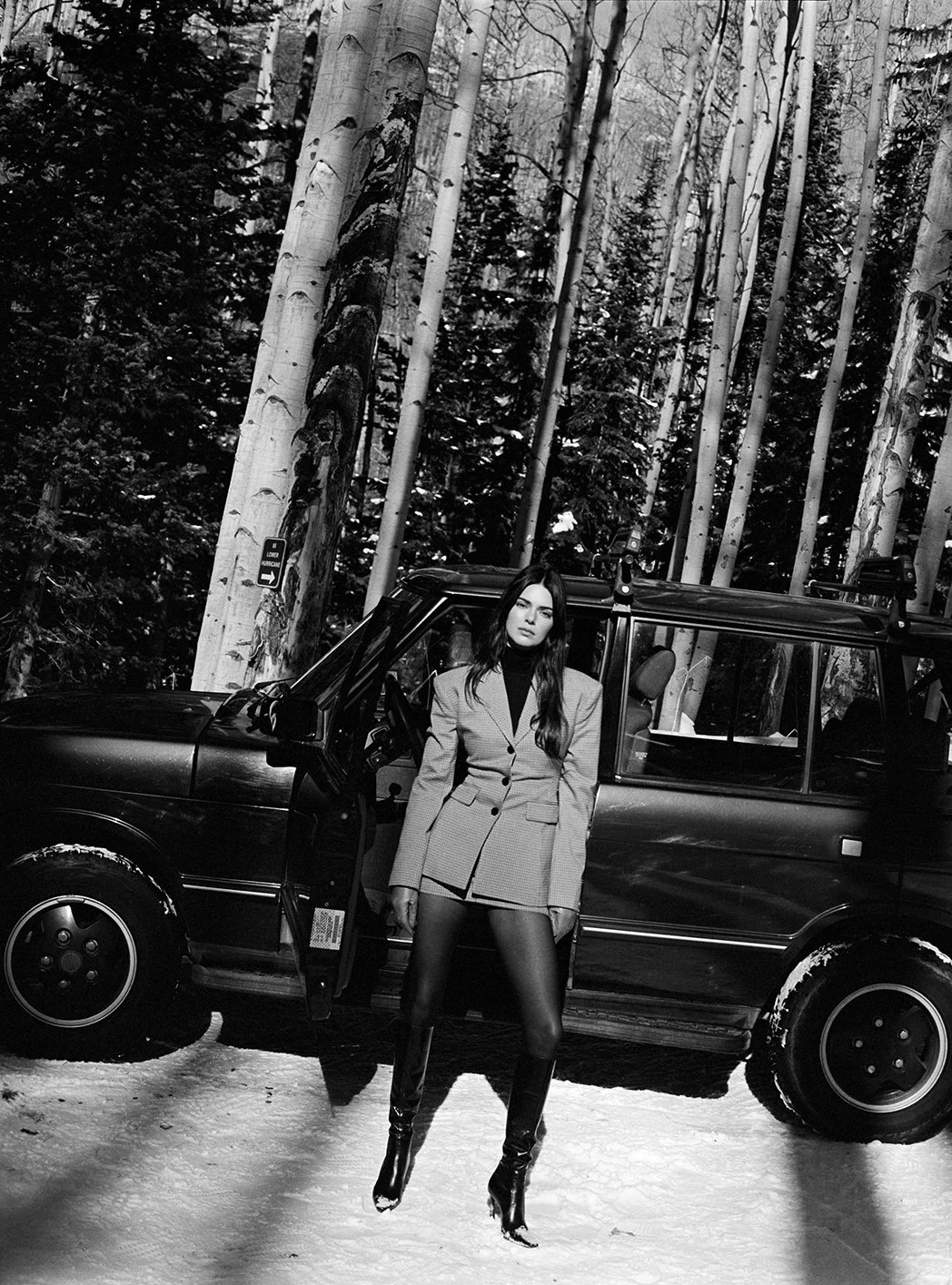  Black-and-white portrait of Kendall Jenner in a tailored winter look beside an SUV in Aspen for FWRD, photographed by Sean Thomas. 