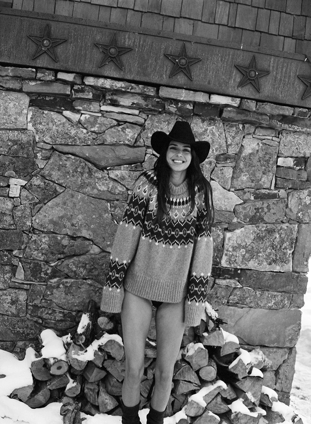  Black-and-white portrait of Kendall Jenner in a patterned sweater and cowboy hat beside a stone wall in Aspen for FWRD, photographed by Sean Thomas. 