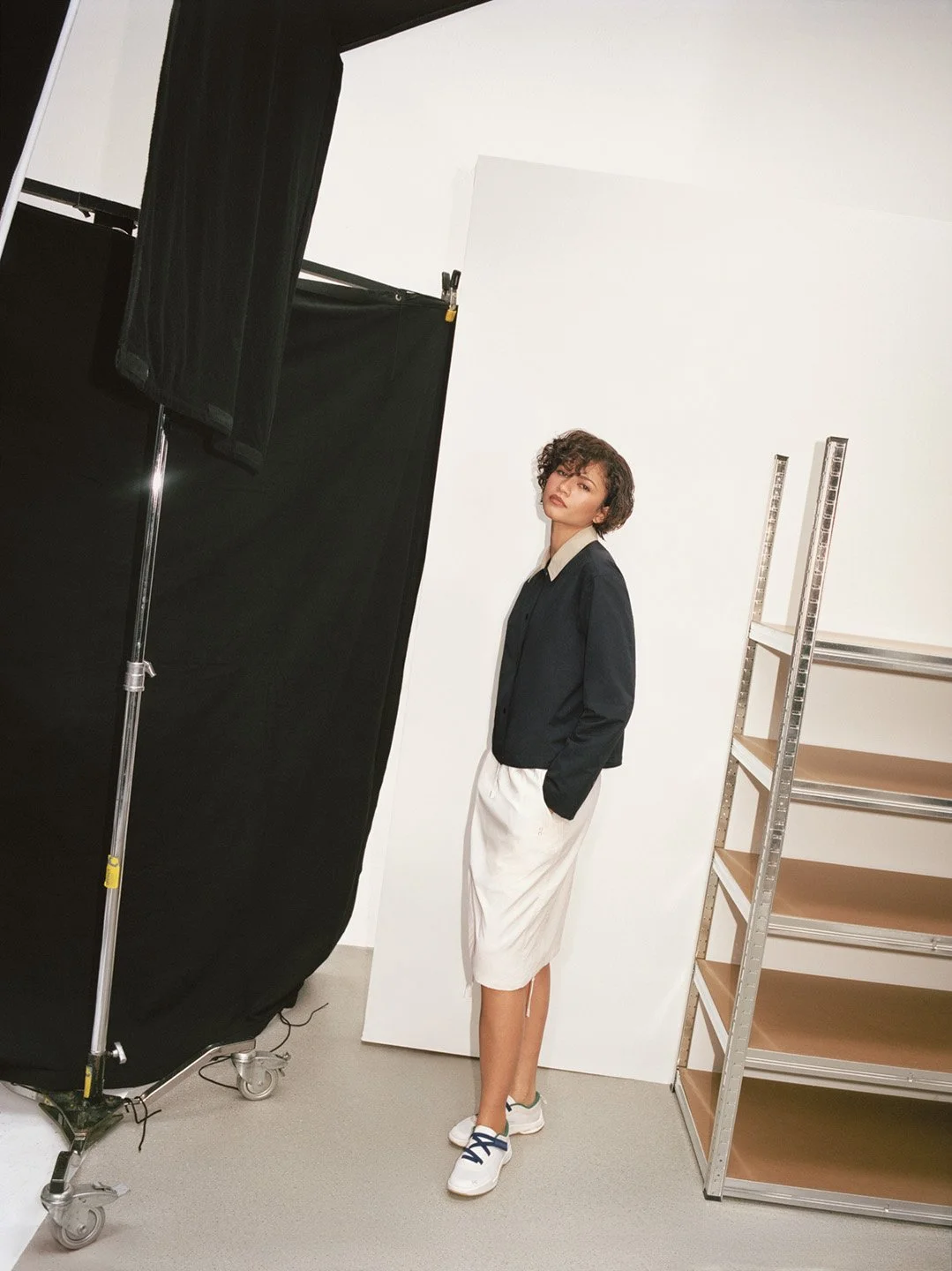  Zendaya standing on a London studio set in a black jacket, white shorts and On sneakers, photographed by Sean Thomas for On. 