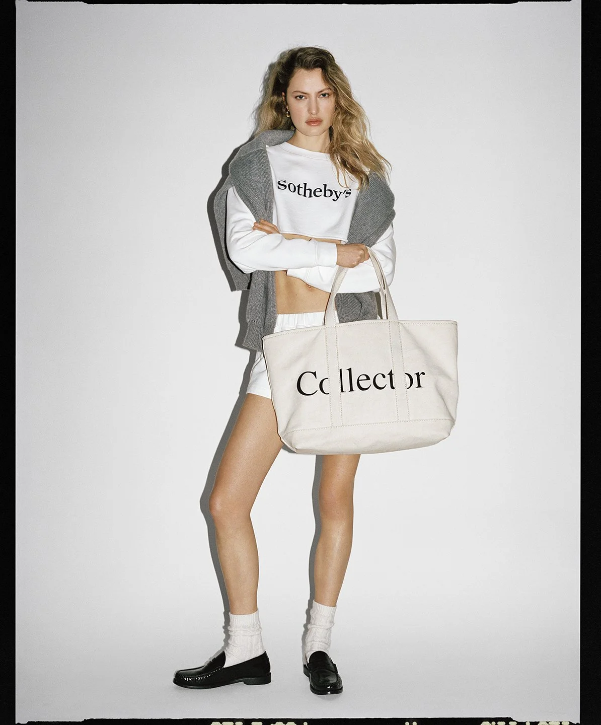  Felice Nova Noordhoff holding a Collector tote in a cropped Sotheby’s sweatshirt and white shorts, photographed by Sean Thomas for FRAME. 