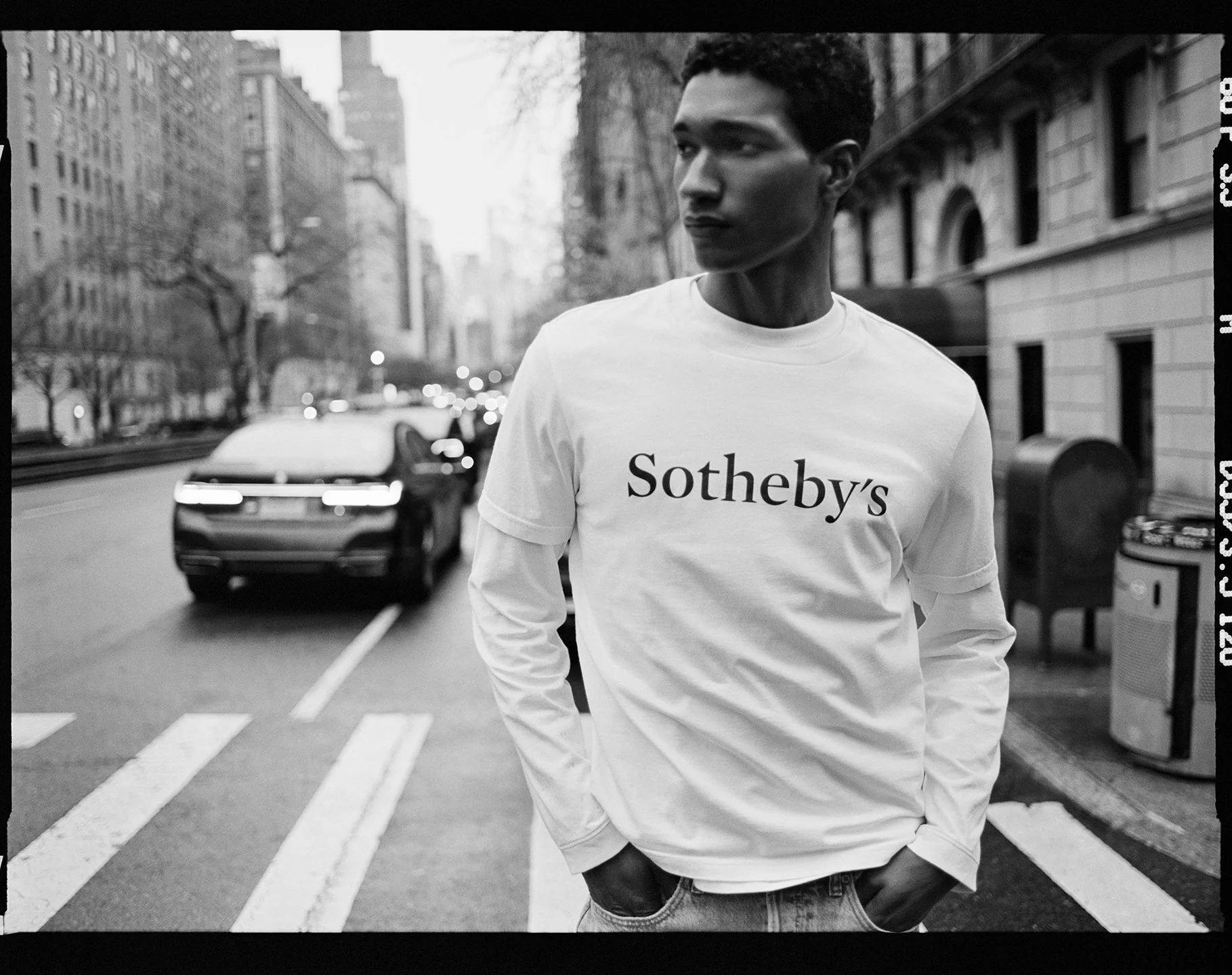  Joshua Seth Williams on a New York street in a white Sotheby’s long-sleeve shirt, photographed in black and white by Sean Thomas. 