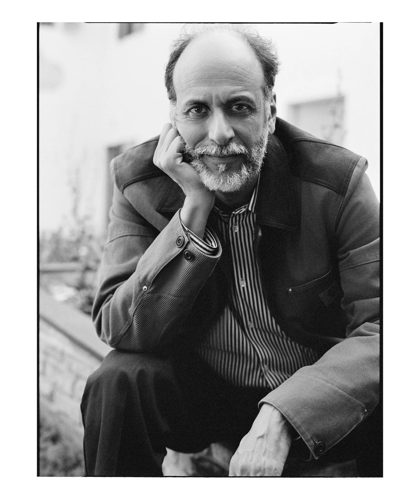  Close black-and-white portrait of filmmaker Luca Guadagnino resting his face on one hand, photographed by Sean Thomas for Door magazine. 