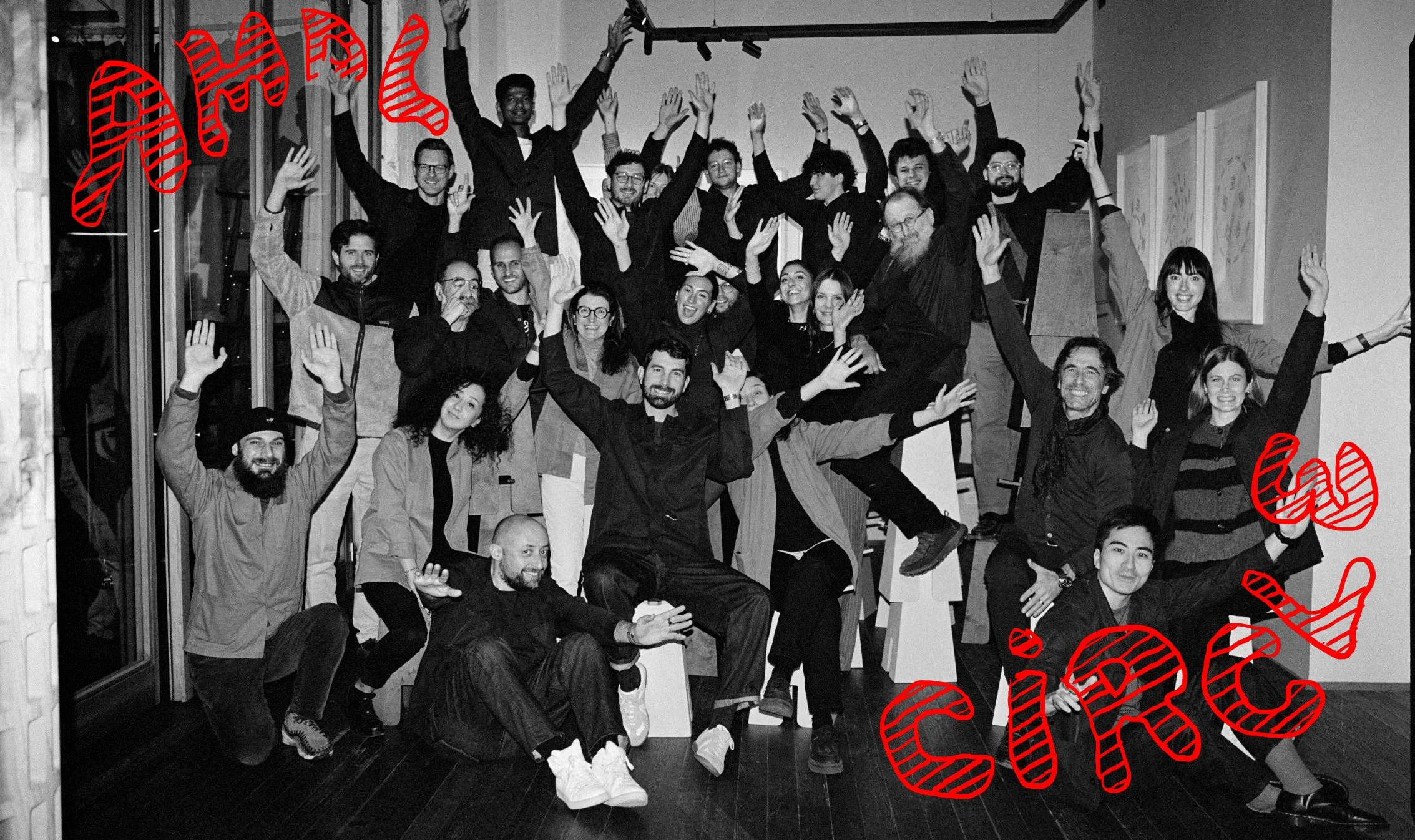  Black-and-white group portrait of the AMDL Circle team raising their hands in the Milan studio, photographed by Sean Thomas for Door’s Salone del Mobile story. 