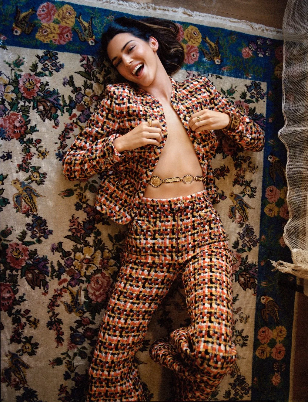  Kendall Jenner laughing on a floral rug in a colorful tweed suit, photographed by Sean Thomas in Laurel Canyon for WSJ. Magazine. 