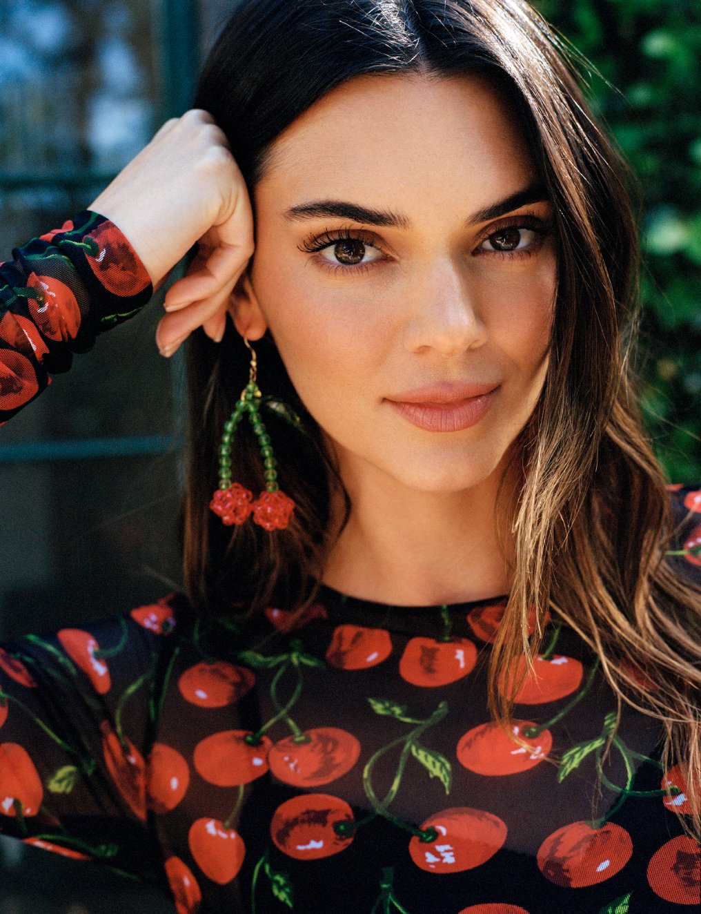  Close portrait of Kendall Jenner in a cherry-print top and beaded cherry earrings, photographed by Sean Thomas in Laurel Canyon for WSJ. Magazine. 